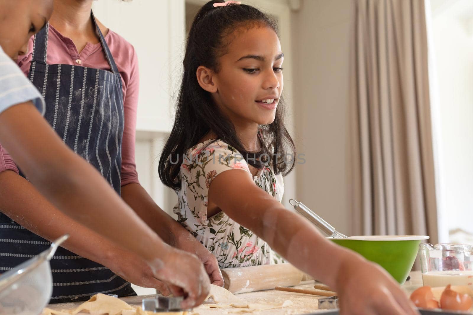 Happy african american mother with son and daughter baking in kitchen, cutting cookies. family enjoying quality free time together.