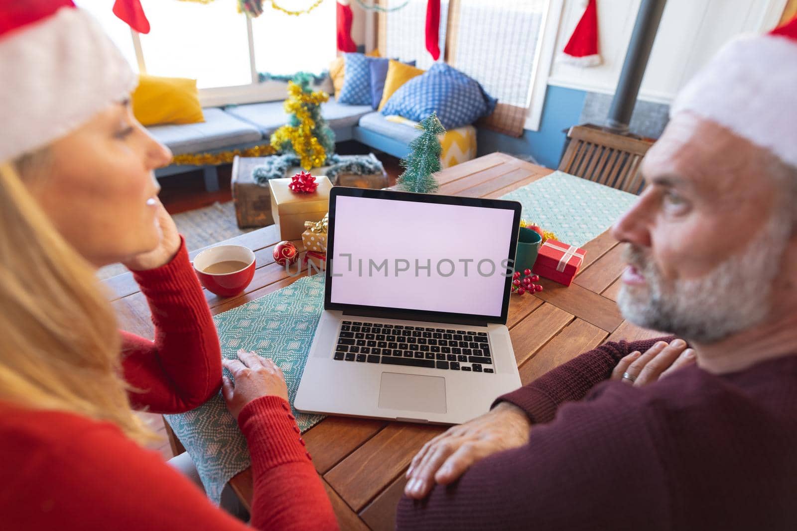 Happy caucasian mature couple making a video call and using laptop with copy space. christmas, festivity and communication technology.