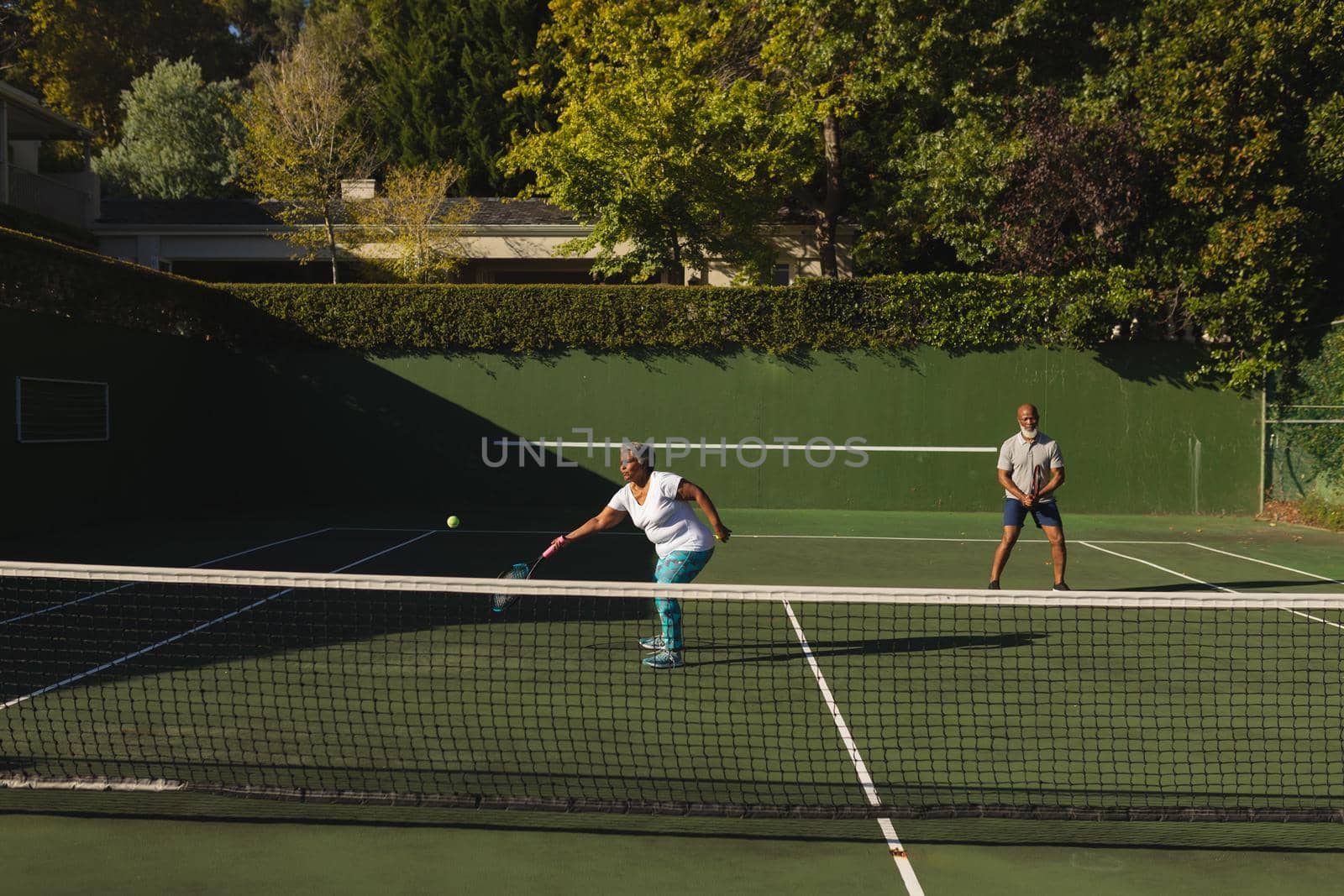 Senior african american couple playing tennis on tennis court by Wavebreakmedia