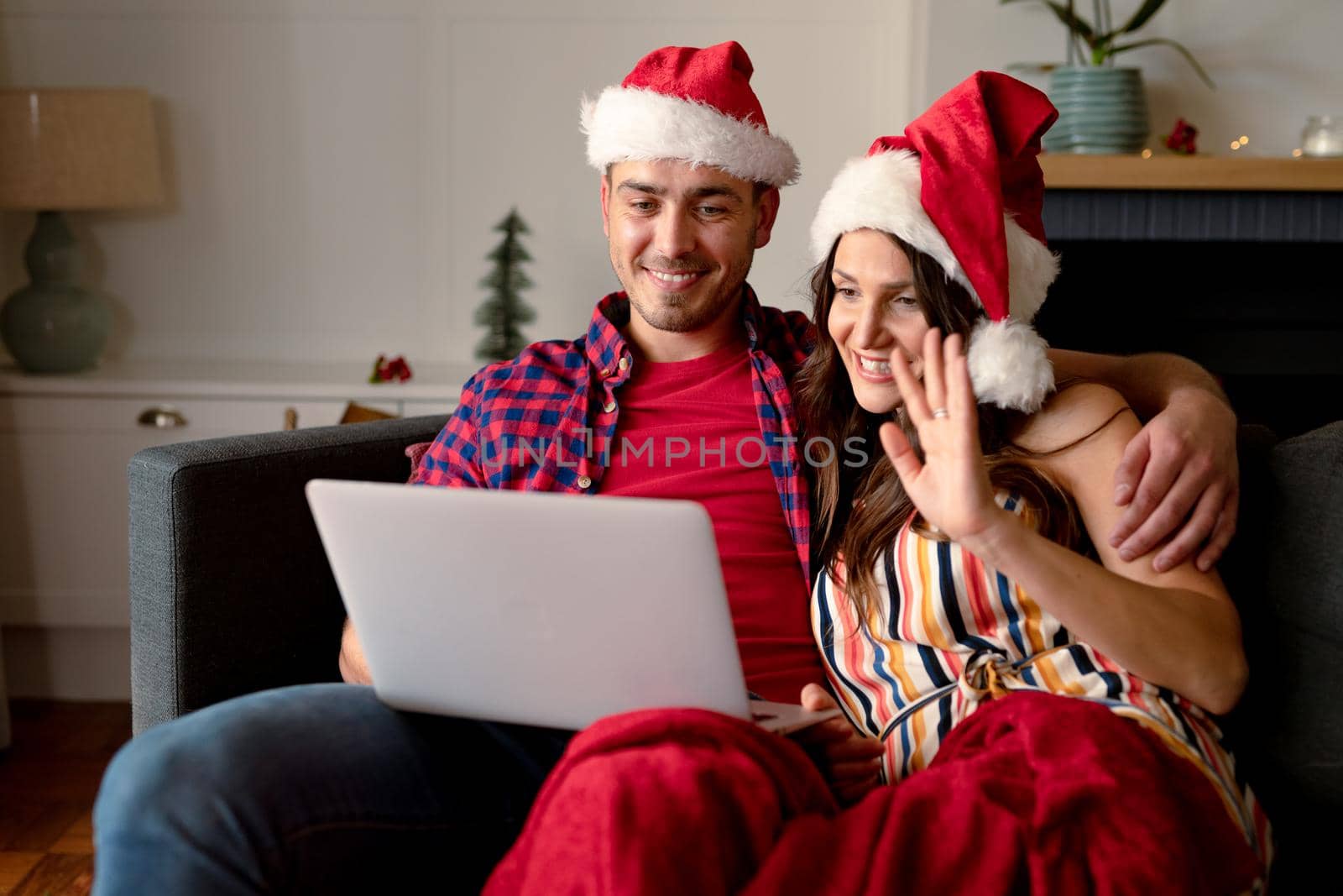 Happy caucasian couple wearing santa hats and having video call on laptop at christmas time by Wavebreakmedia