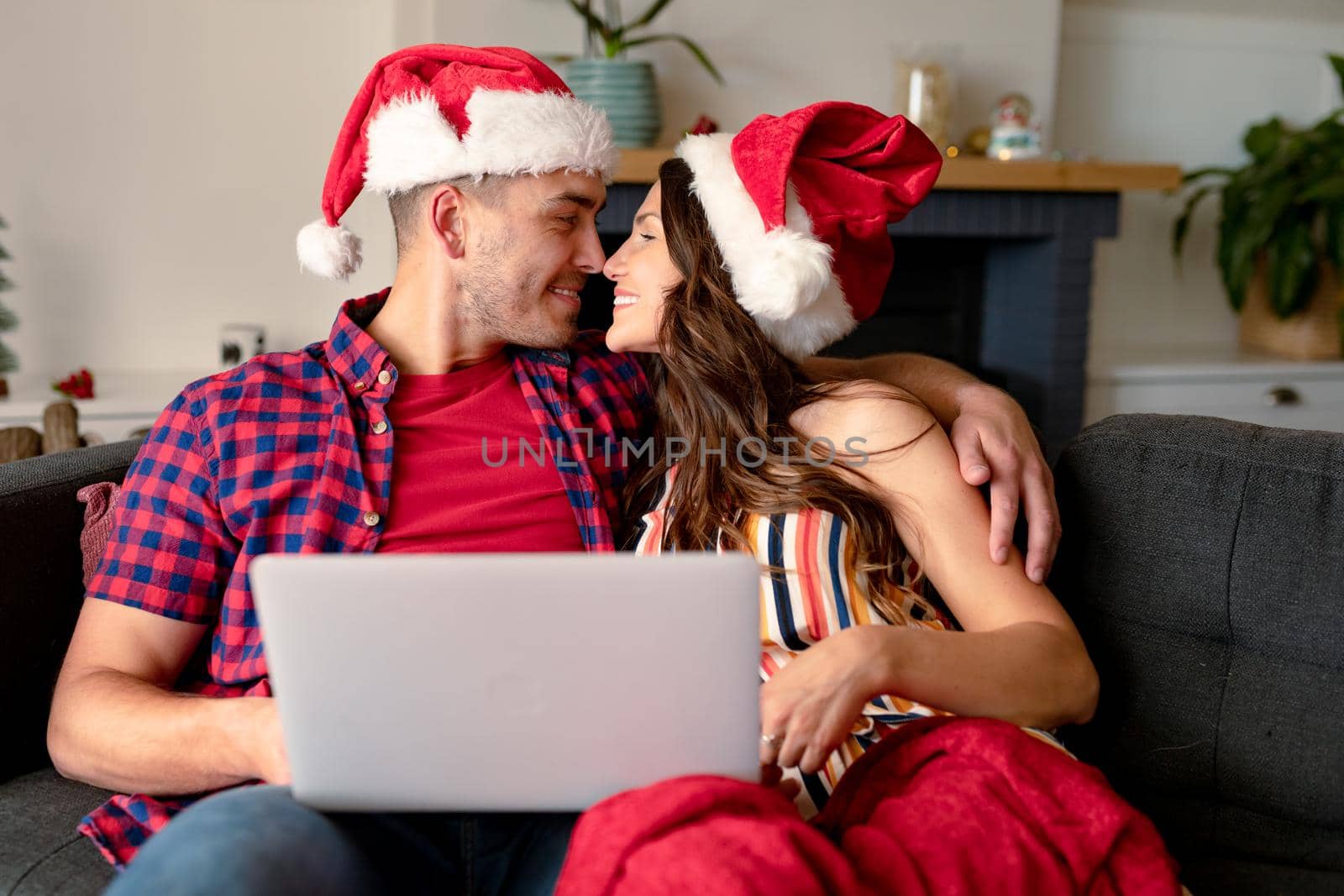 Happy caucasian couple wearing santa hats, hugging and having video call on laptop at christmas time by Wavebreakmedia