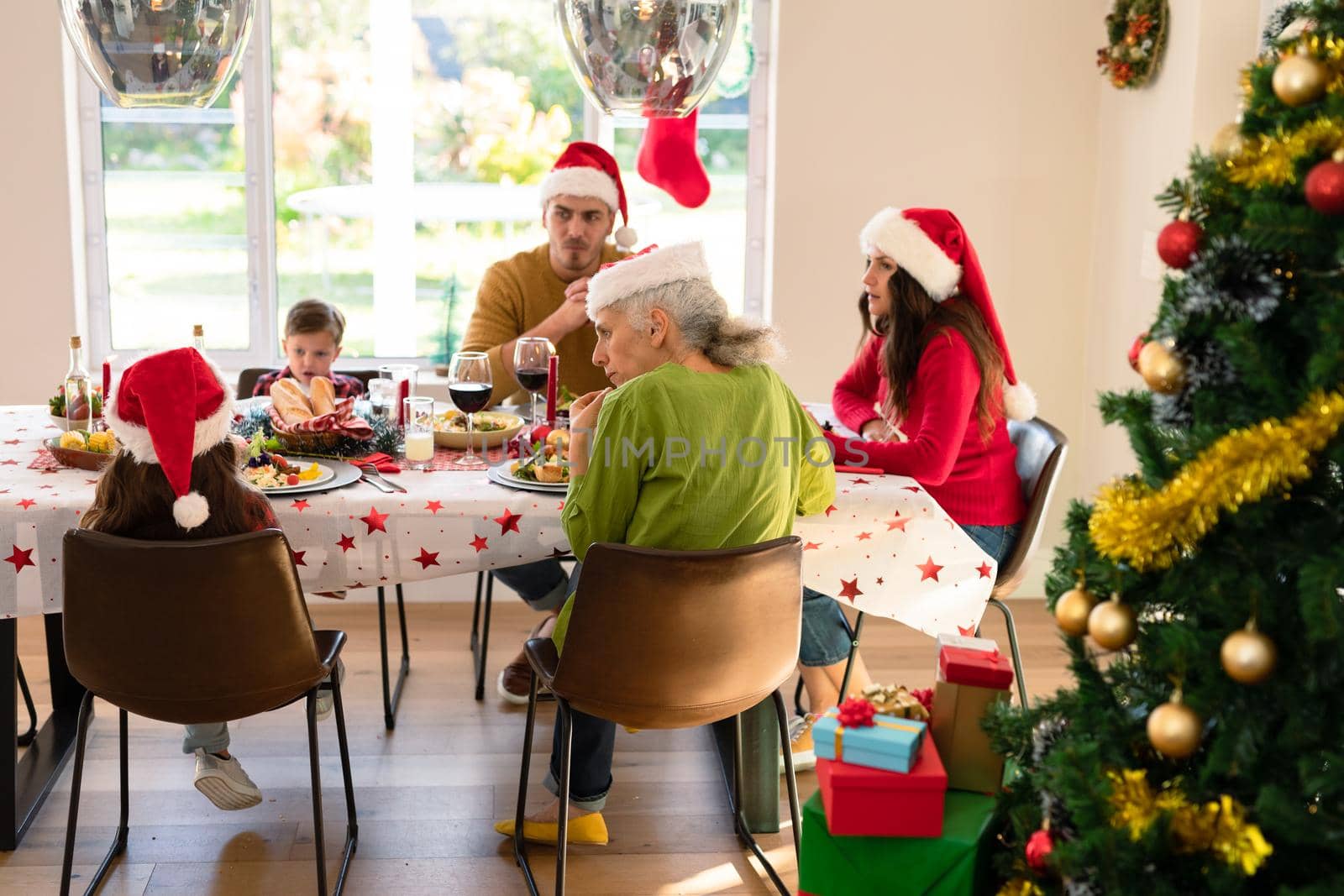 Caucasian multi generation family wearing santa hats having christmas meal by Wavebreakmedia