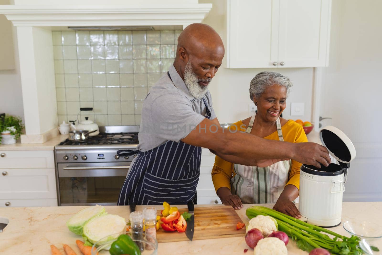 Senior african american couple cooking together in kitchen smiling. retreat, retirement and happy senior lifestyle concept.