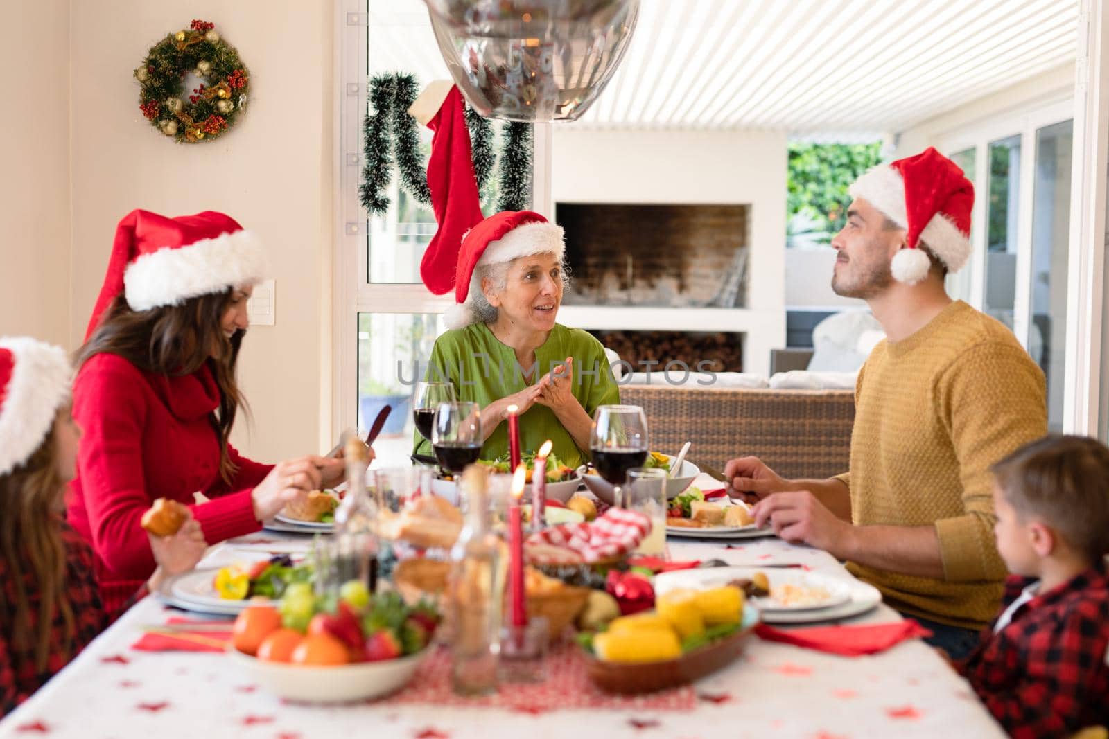 Happy caucasian multi generation family wearing santa hats sitting at christmas table. family christmas time and festivity together at home.