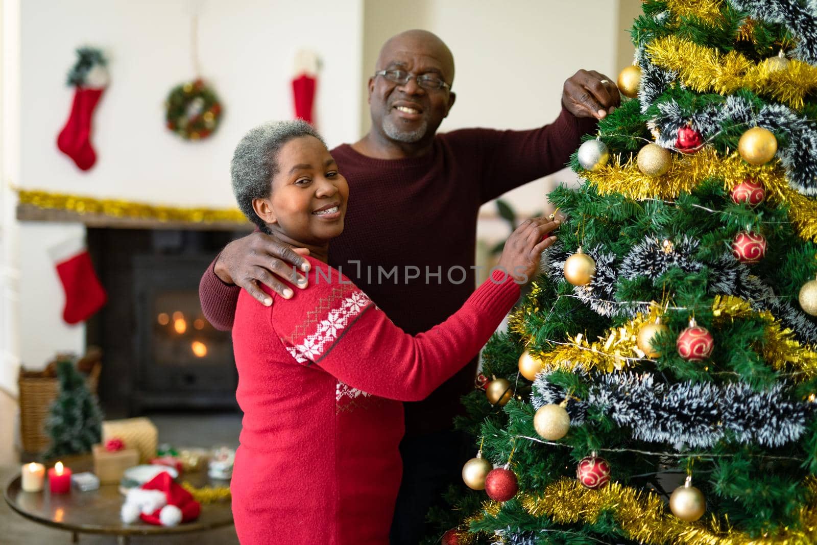 Happy african american senior couple decorating christmas tree at christmas time. retirement lifestyle and christmas festivities, celebrating at home.