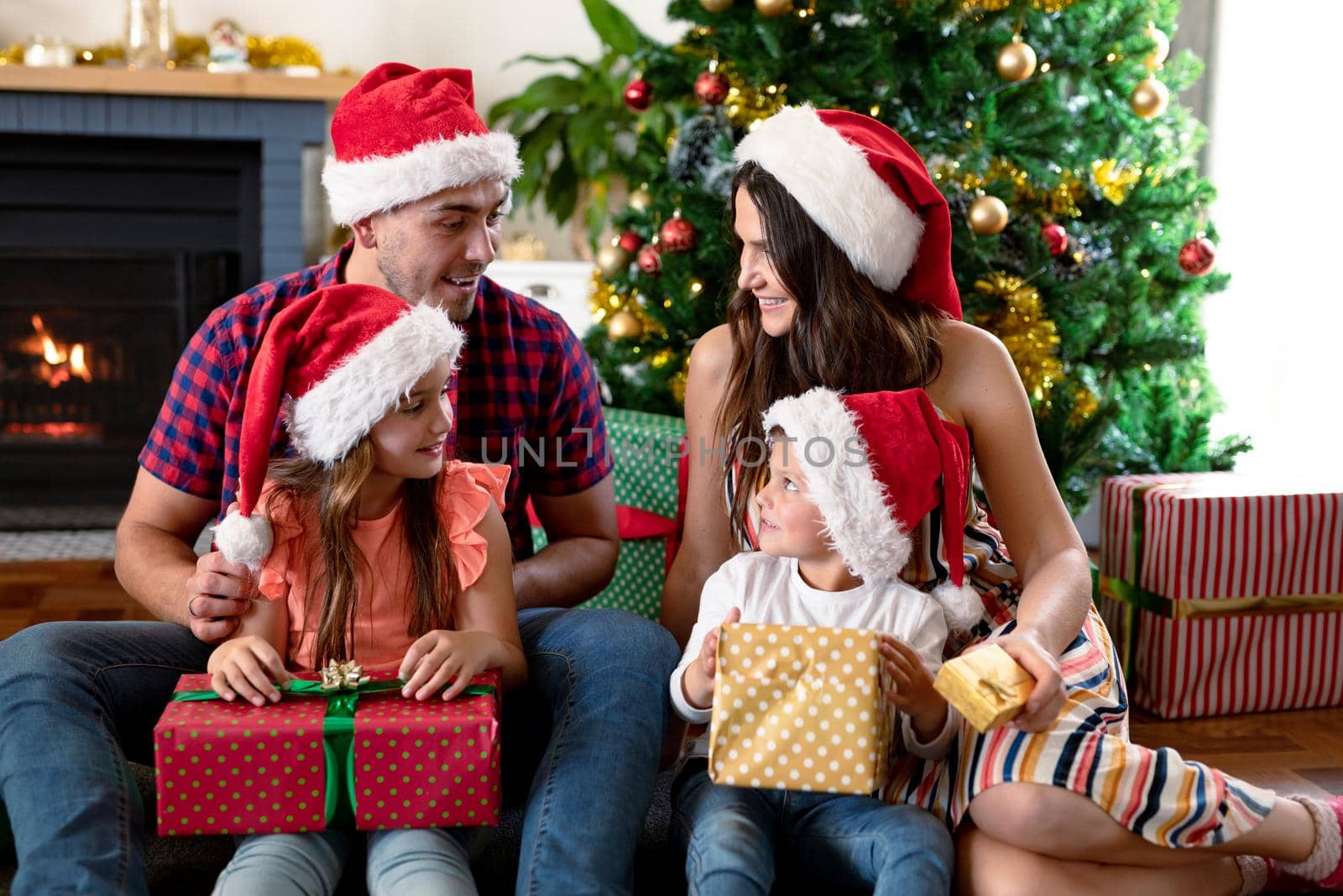 Happy caucasian family wearing santa hat, holding present at christmas times. family christmas time and festivity together at home.