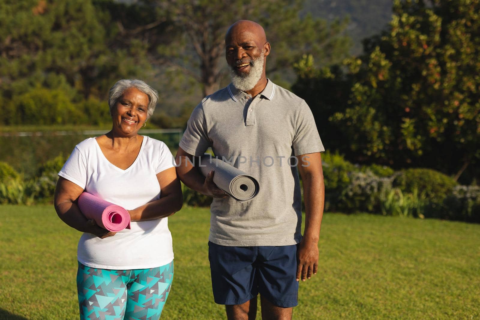 Portrait of smiling senior african american couple with yoga mat in countryside retreat. retirement and active senior lifestyle concept.