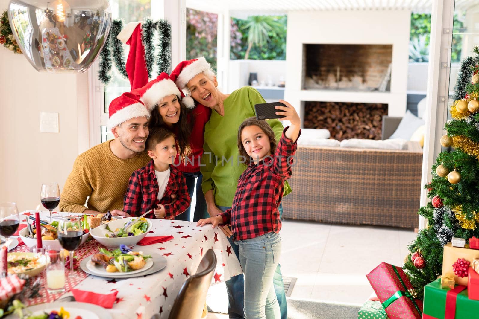 Caucasian multi generation family wearing santa hats taking selfie at christmas time. family christmas time and festivity together at home.