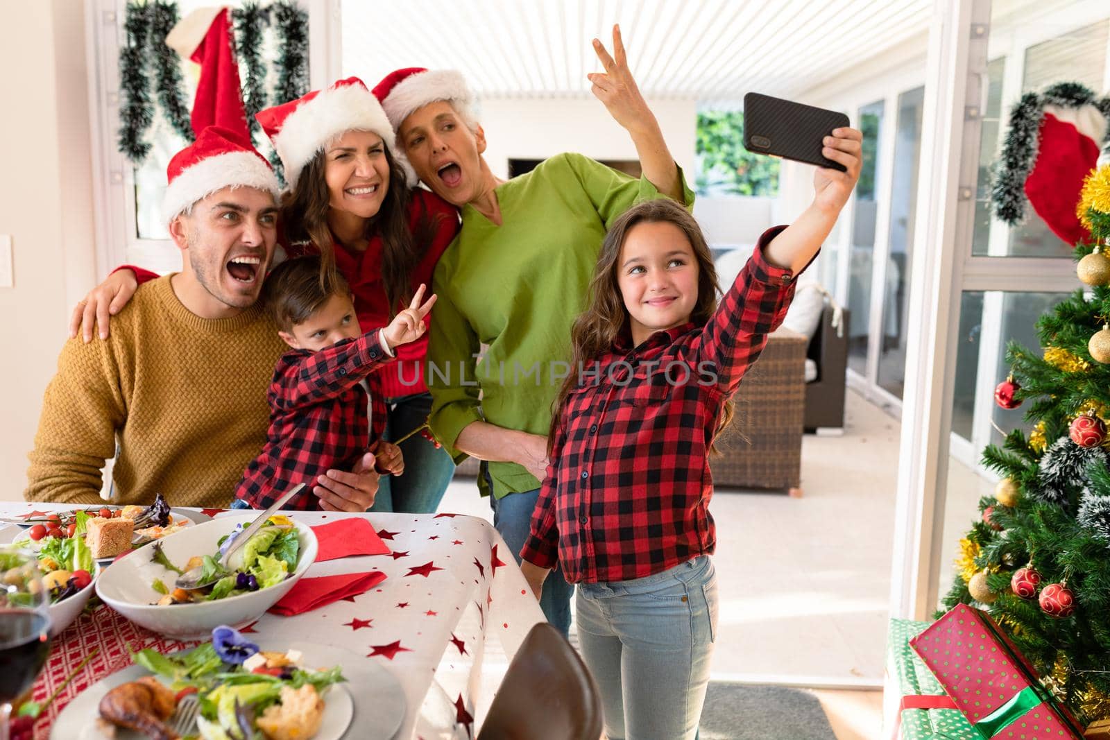 Caucasian multi generation family wearing santa hats taking selfie at christmas time. family christmas time and festivity together at home.