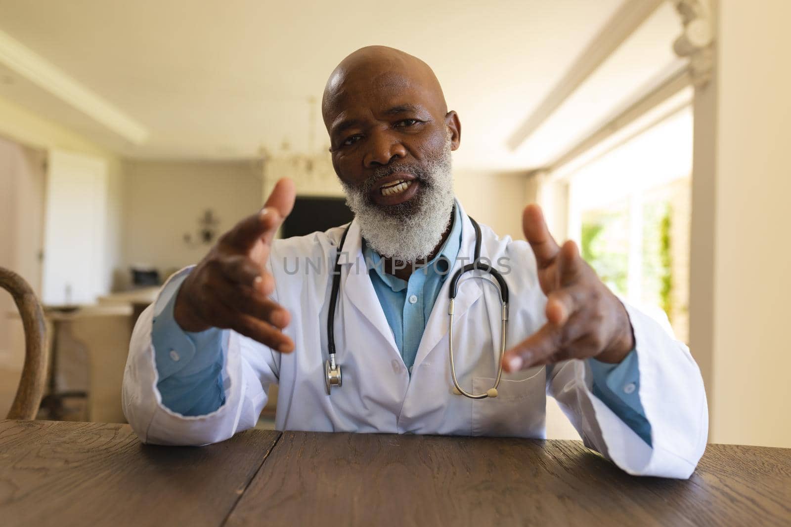 Portrait of smiling senior african american male doctor in lab coat during video consultation. medicine and healthcare services concept.