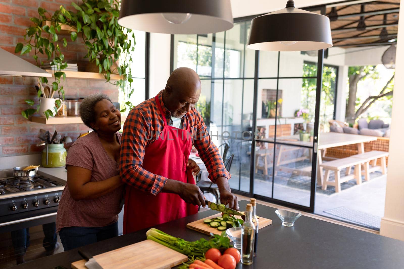 Happy african american senior couple cooking together in kitchen. retirement lifestyle, leisure and spending time at home.