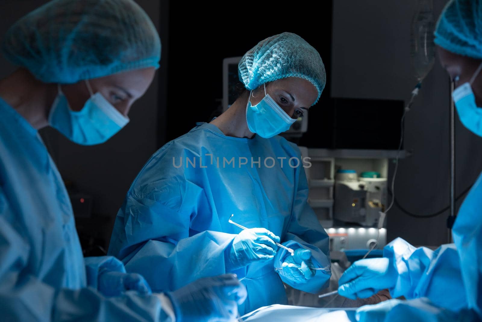 Diverse group of male and female surgeons in operating theatre wearing face masks performing surgery. medicine, health and healthcare services during coronavirus covid 19 pand