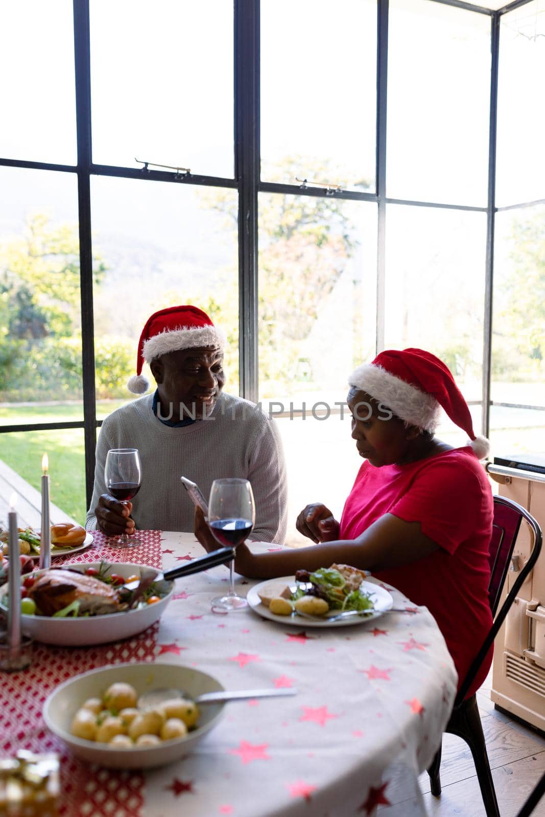 African american senior couple in santa hats using smartphone at christmas time by Wavebreakmedia