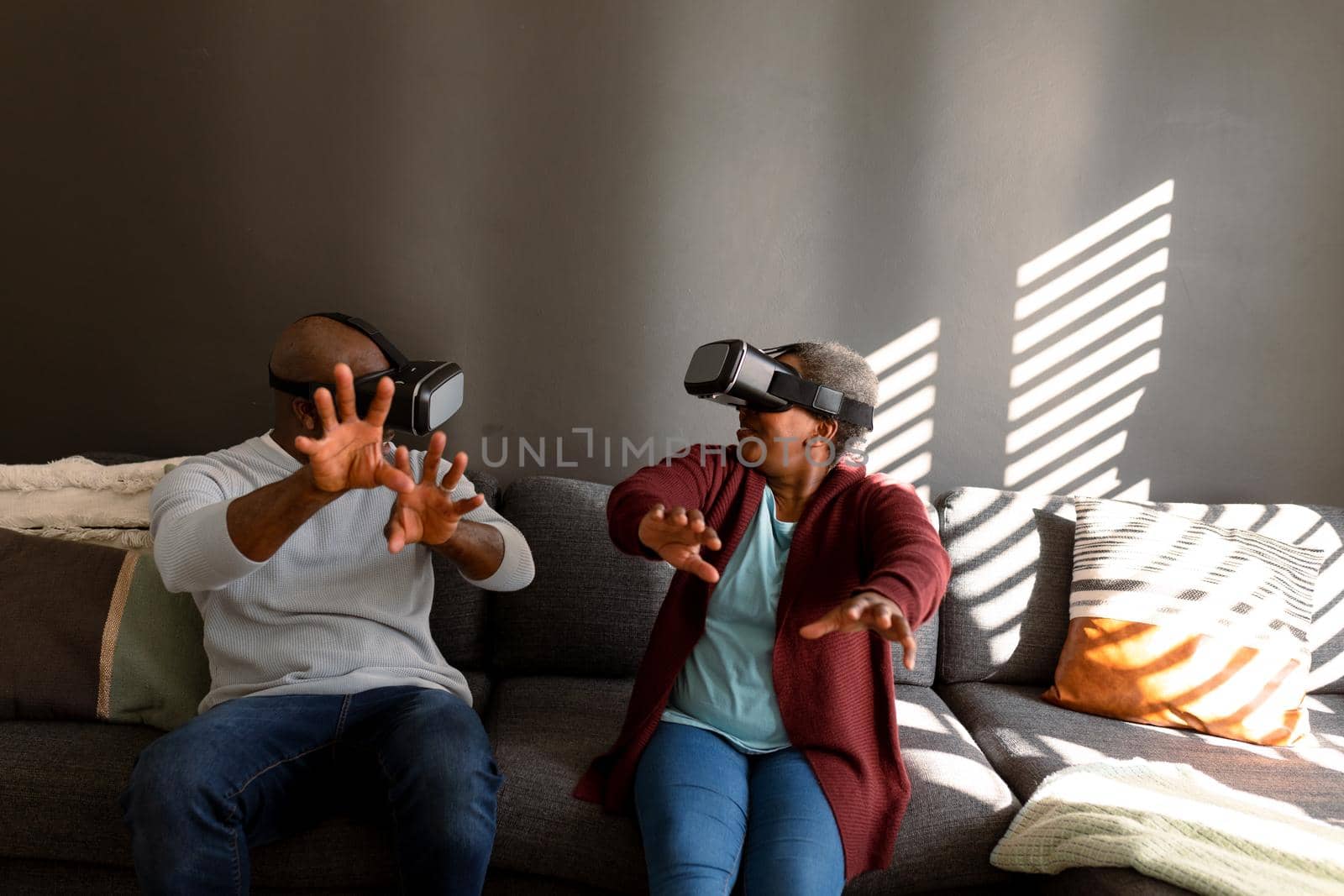 Happy african american senior couple wearing vr headset and having fun at home. retirement lifestyle, technology and spending time at home.