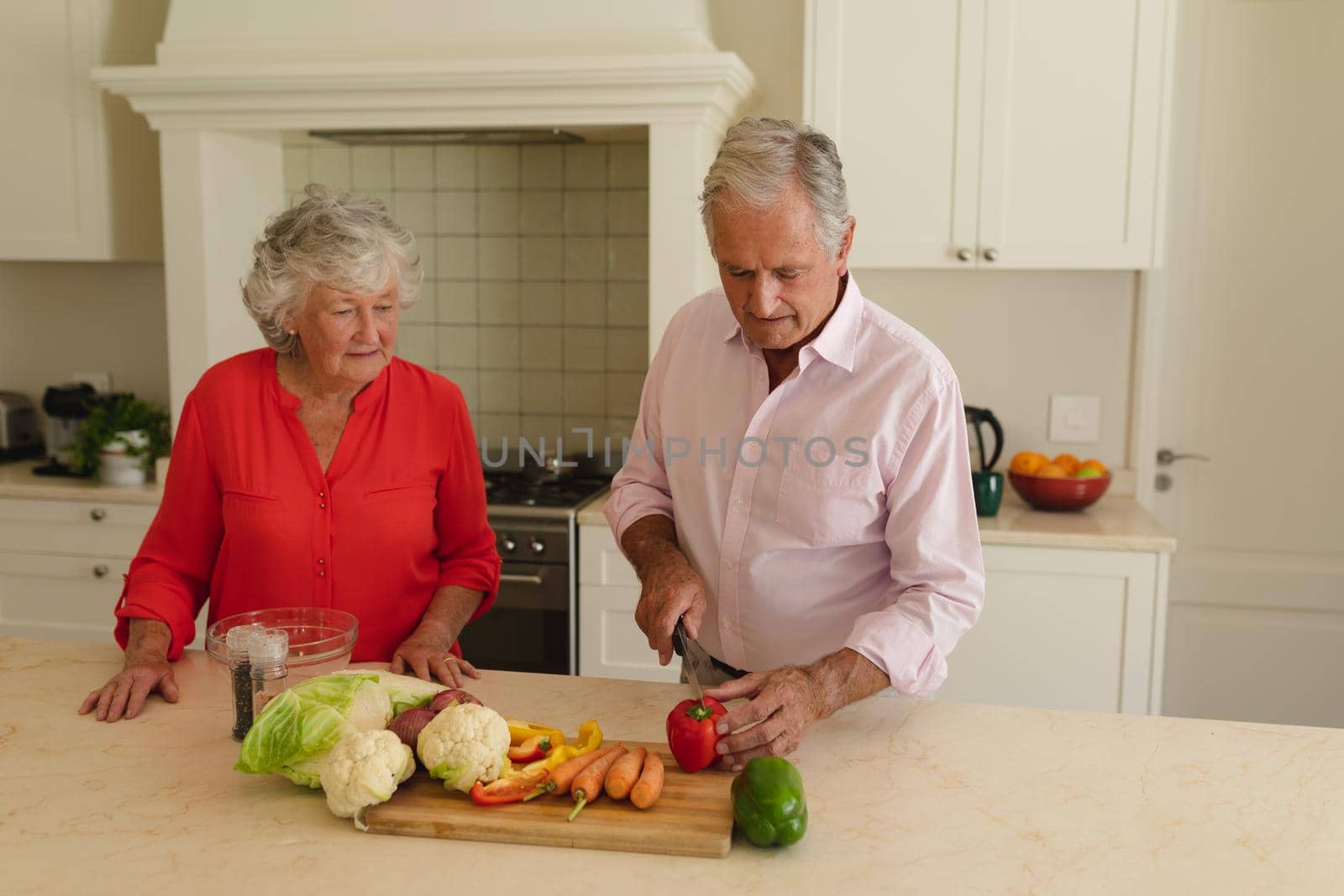 Senior caucasian couple cooking together and talking in kitchen. retreat, retirement and happy senior lifestyle concept.