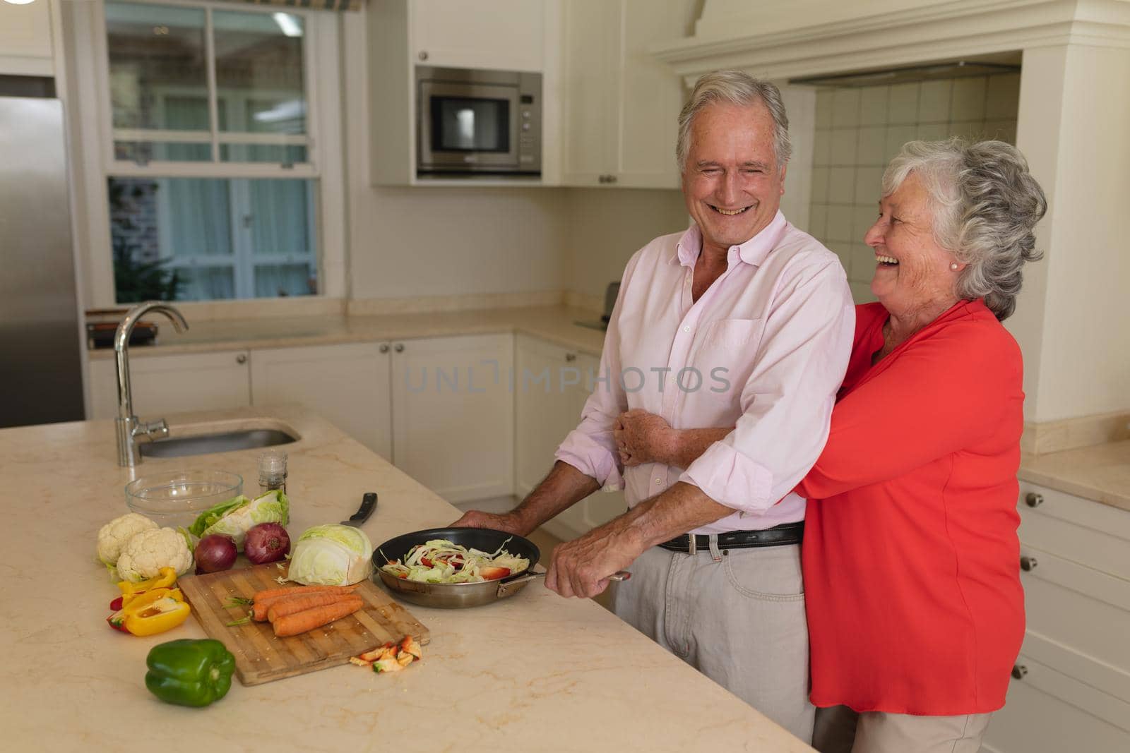 Senior caucasian couple cooking together and smiling in kitchen. retreat, retirement and happy senior lifestyle concept.
