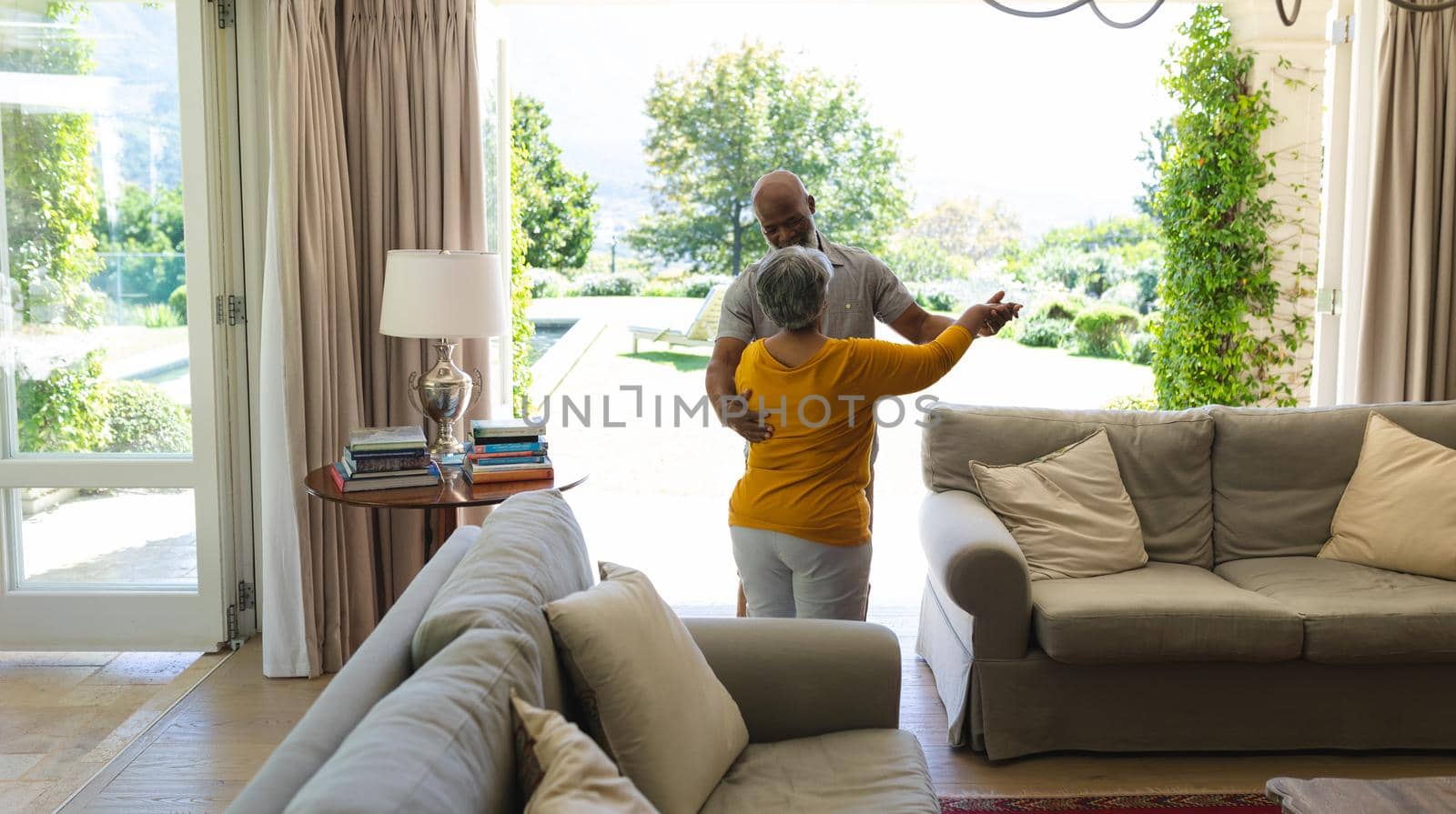 Senior african american couple dancing together in living room. retreat, retirement and happy senior lifestyle concept.
