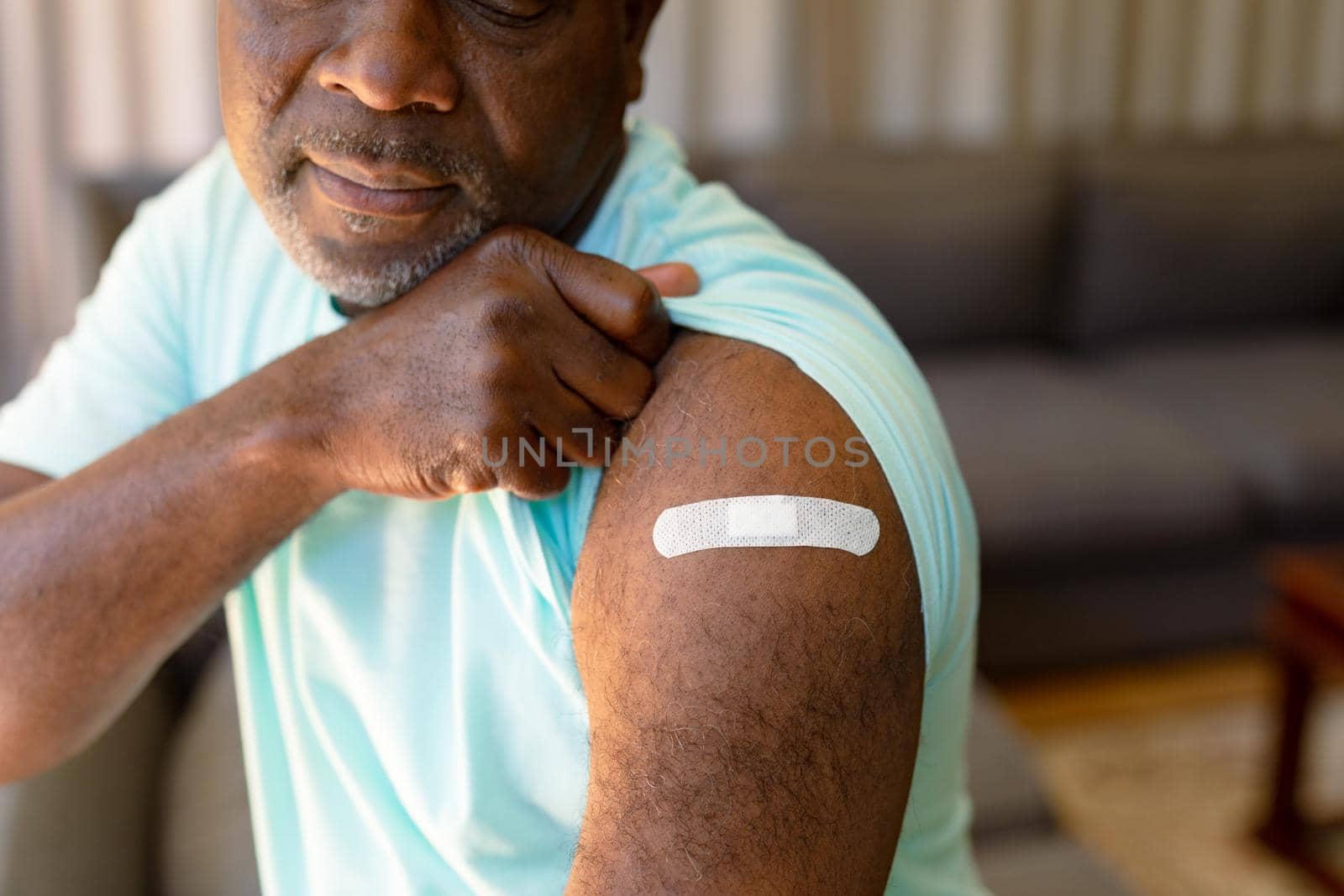 African american senior man showing plaster after vaccination. senior health and lifestyle during covid 19 pandemic.