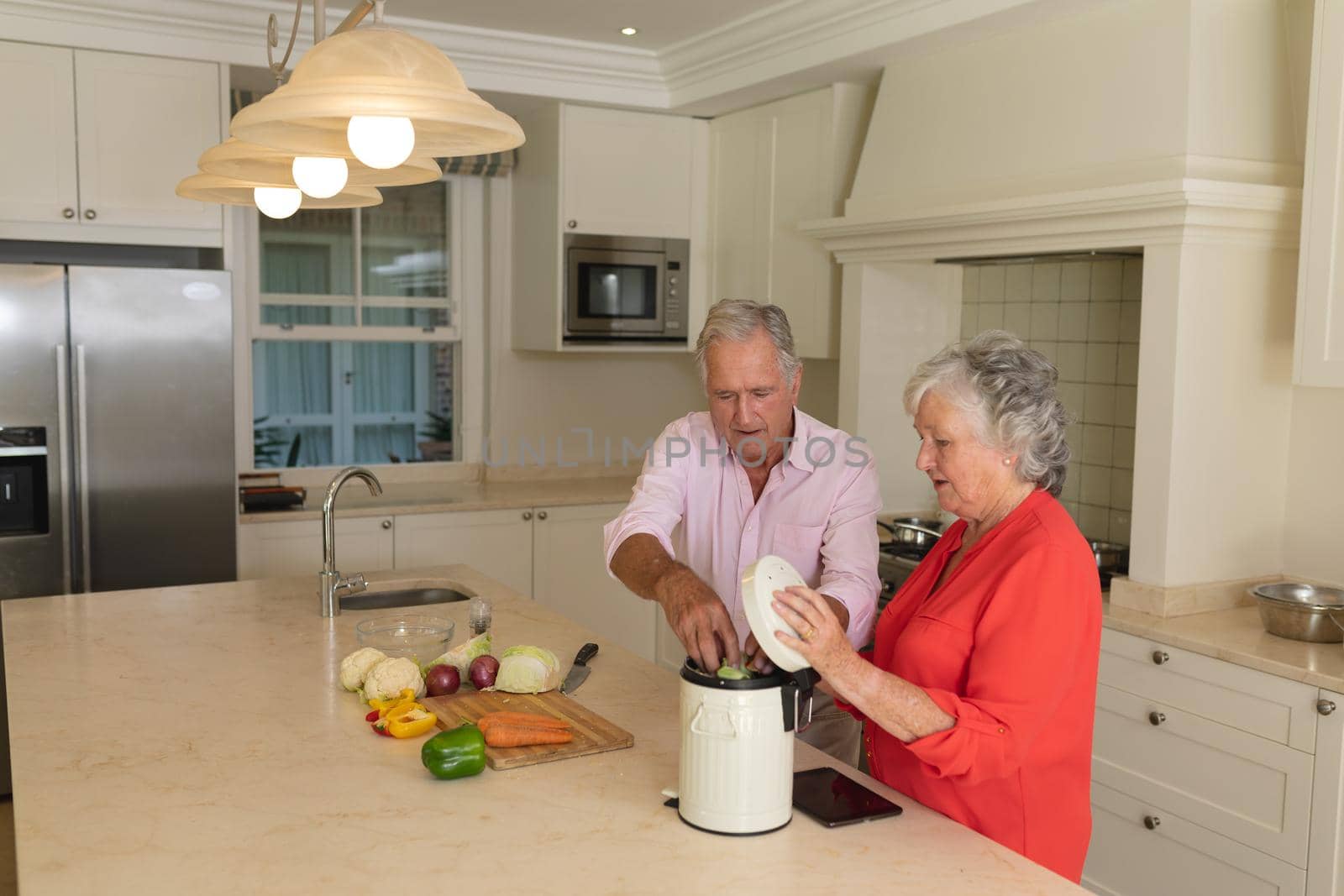 Senior caucasian couple cooking together and talking in kitchen. retreat, retirement and happy senior lifestyle concept.