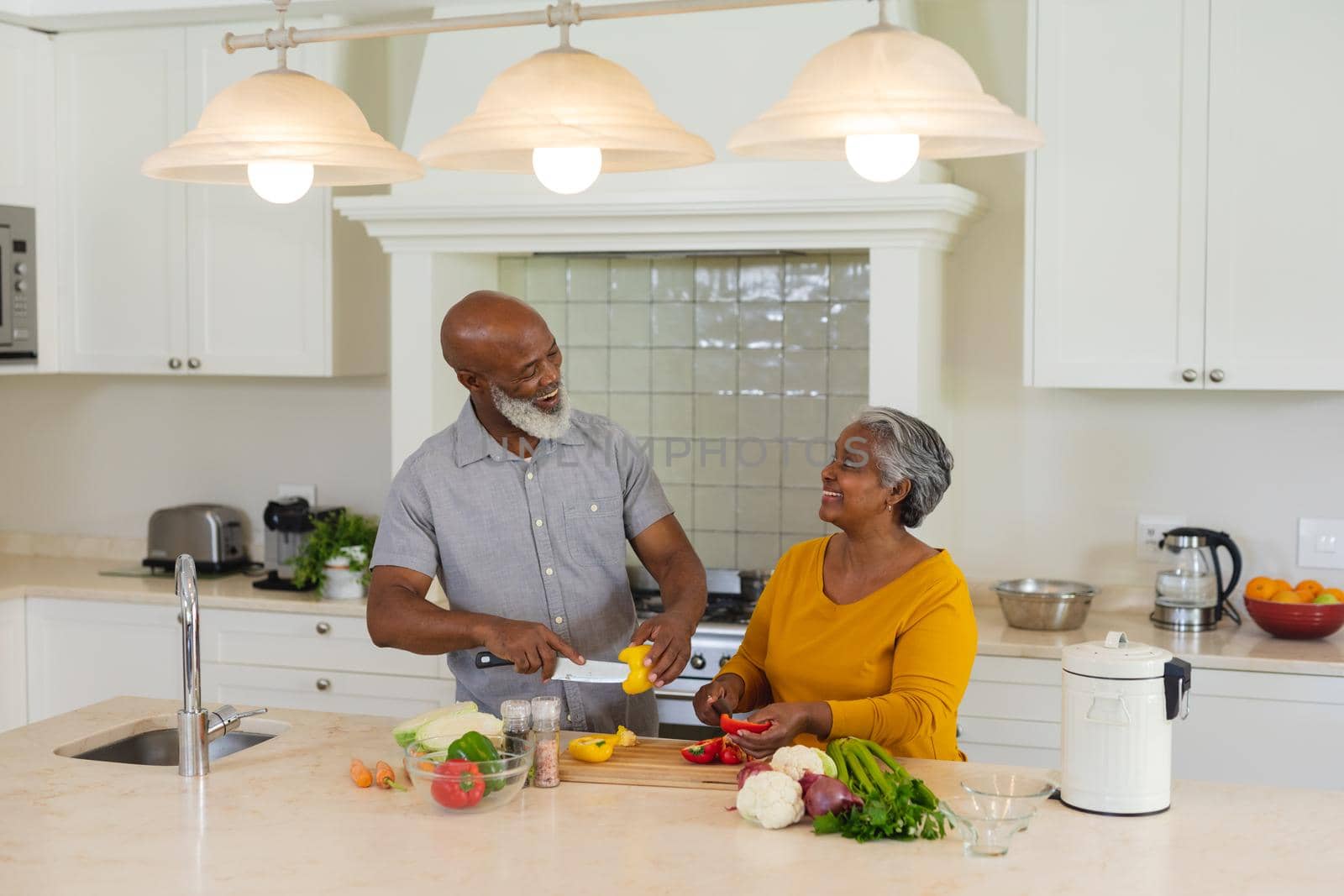 Senior african american couple cooking together in kitchen smiling by Wavebreakmedia