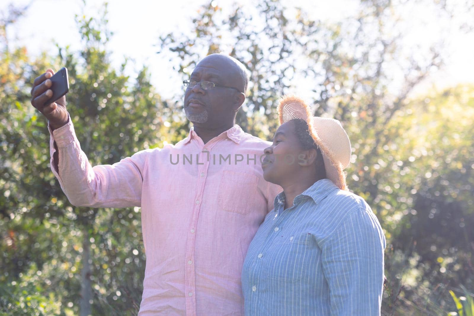 Happy african american senior couple taking selfie outdoors. retirement lifestyle, spending time at home and garden.