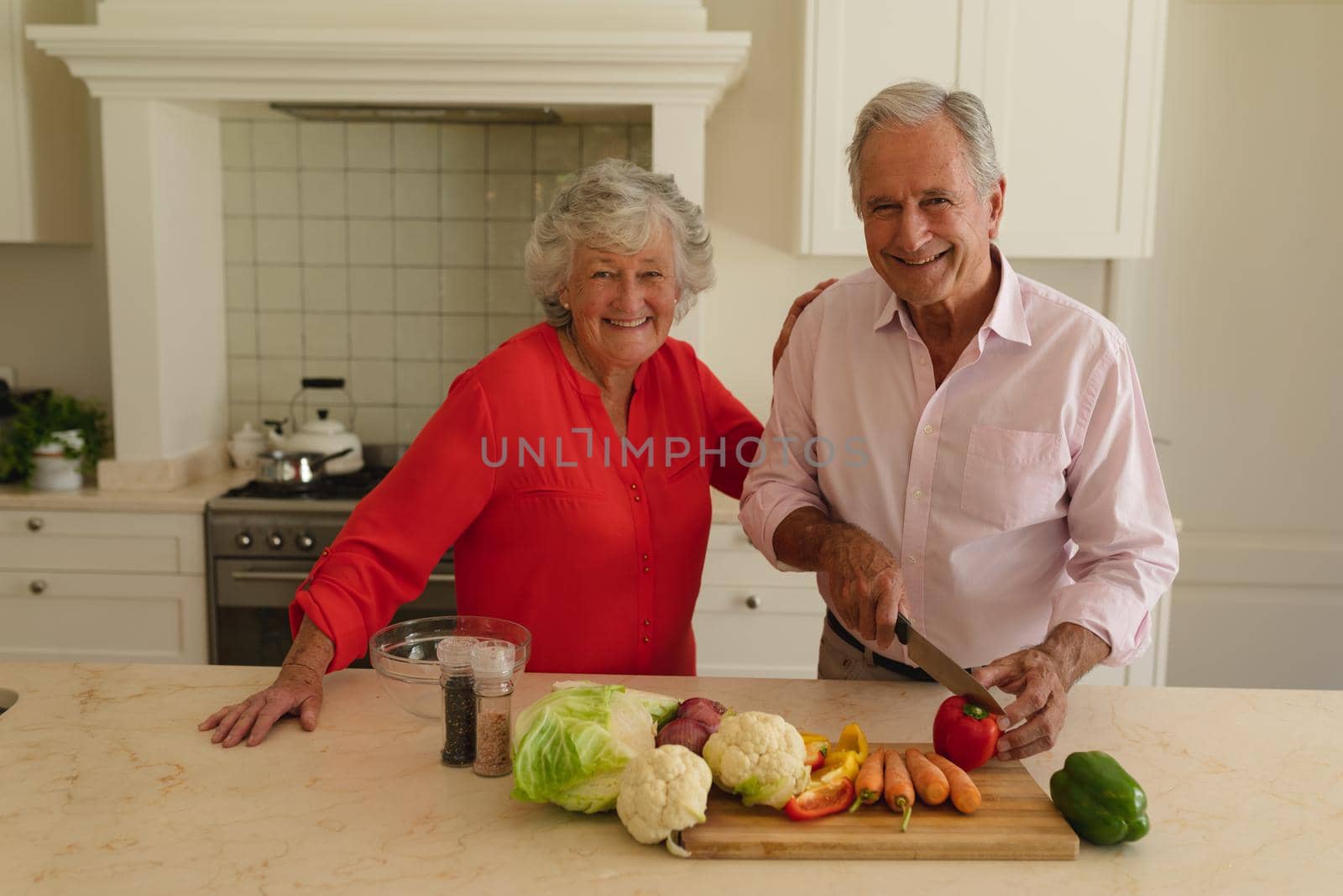 Portrait of senior caucasian couple cooking together and smiling in kitchen. retreat, retirement and happy senior lifestyle concept.