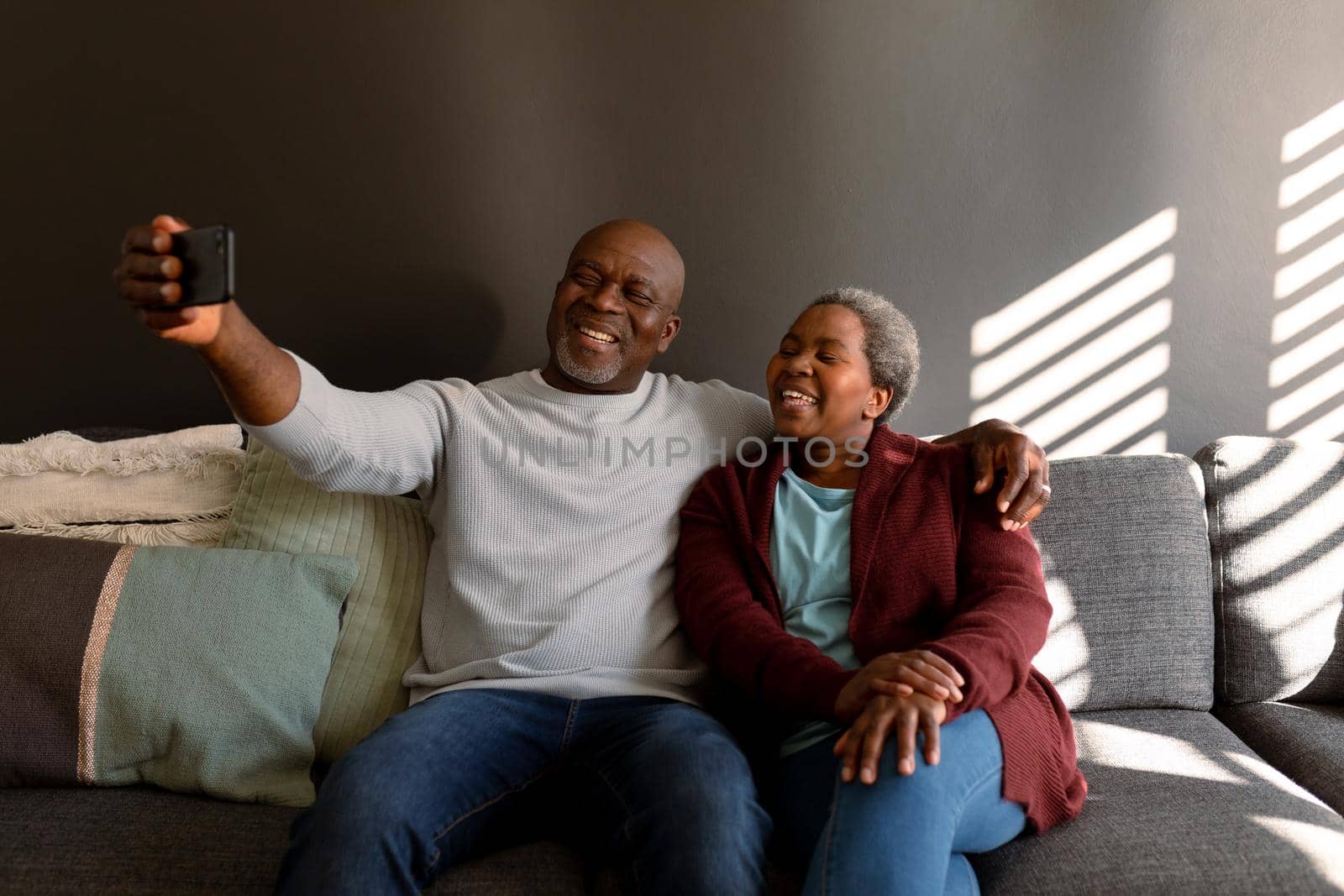 Happy african american senior couple taking selfie at home. retirement lifestyle, communication technology and spending time at home.