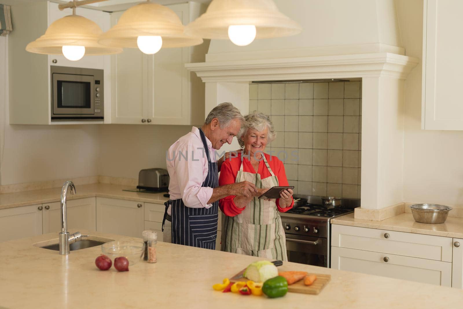 Senior caucasian couple using tablet together in kitchen. retreat, retirement and happy senior lifestyle concept.