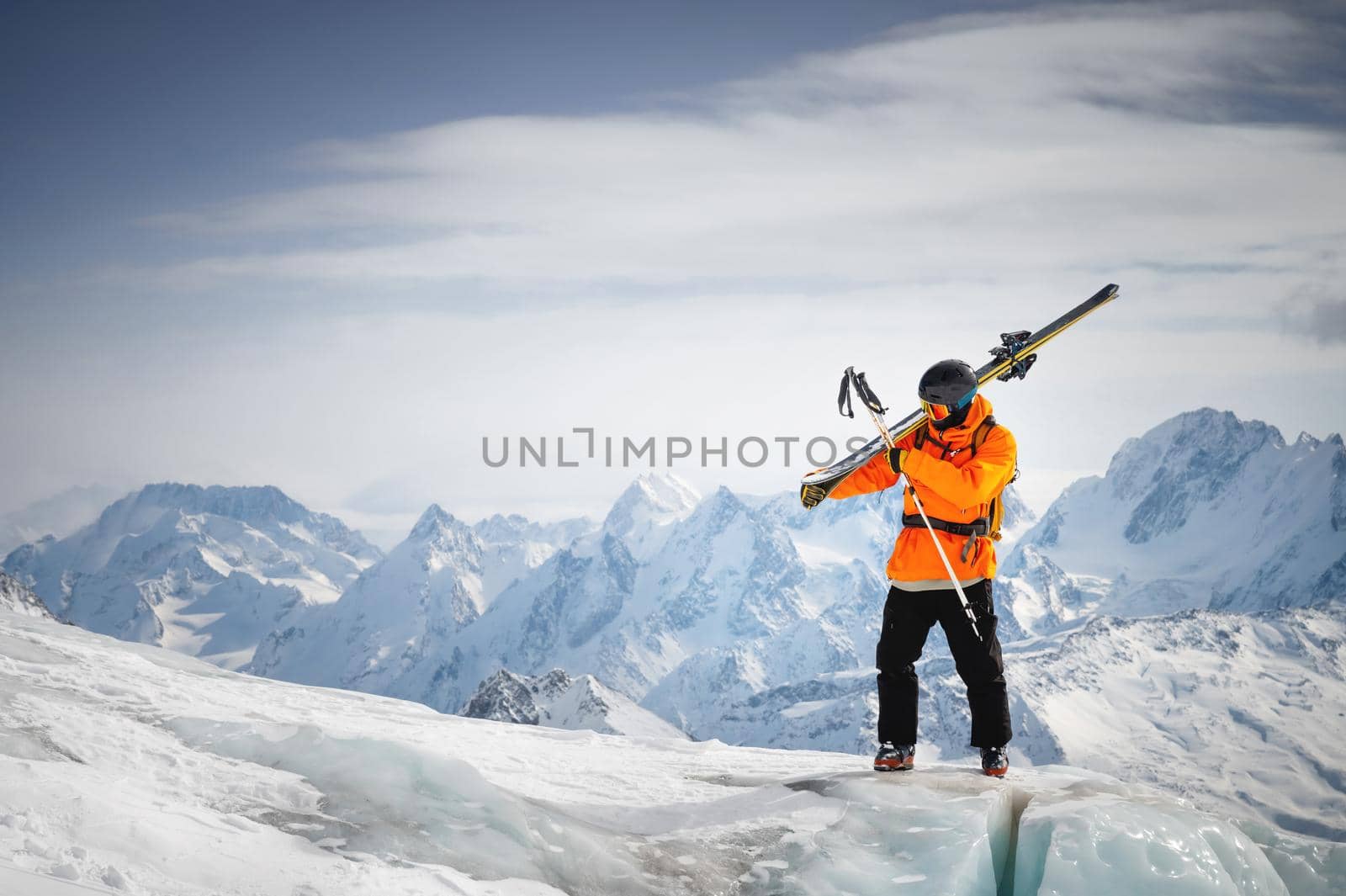 Portrait of a young skier with skis on his shoulder. It stands high in the mountains on a glacier against the backdrop of high mountains. The concept of freeride and backcountry in the highlands by yanik88