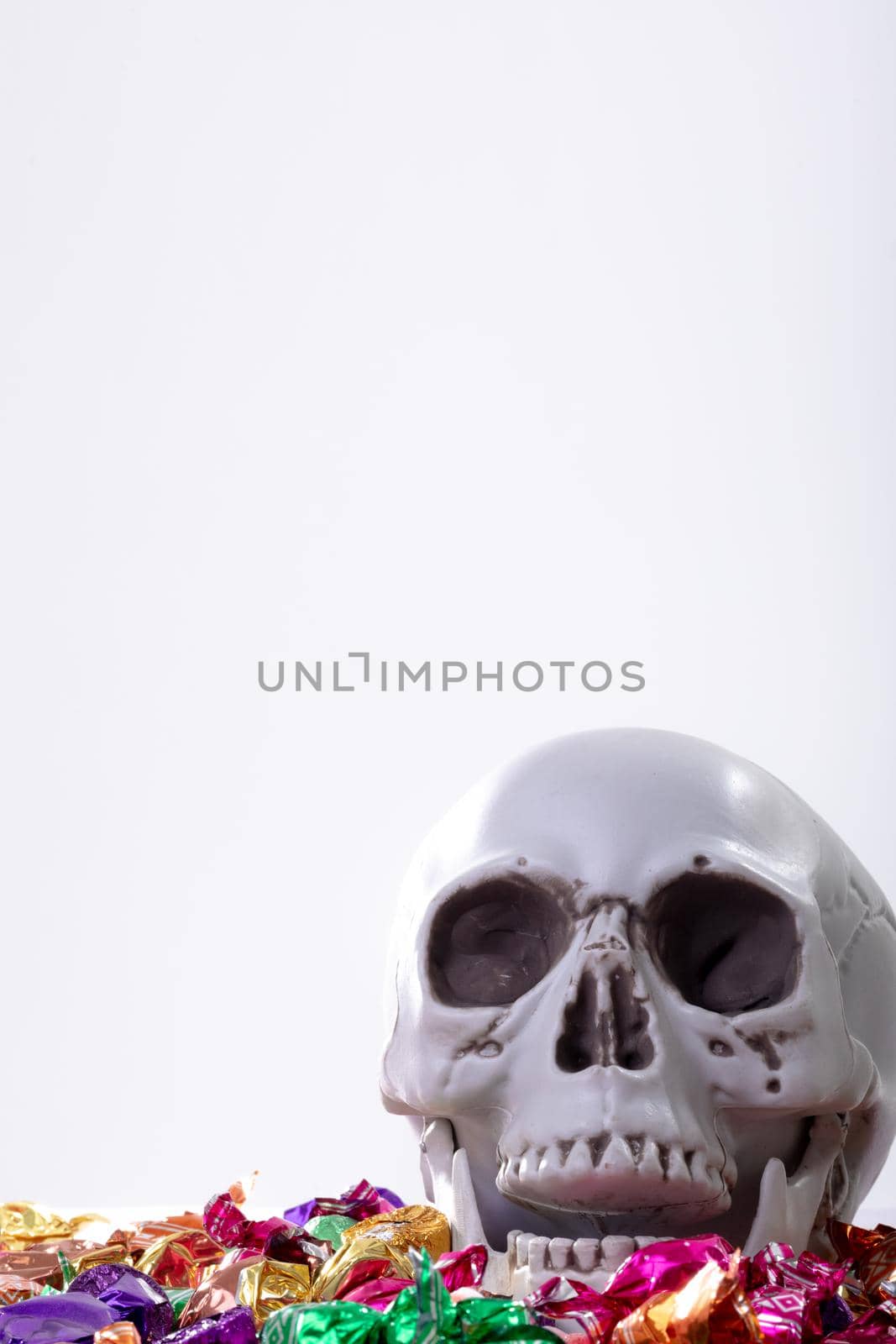 Composition of halloween laughing skull with trick or treat sweets on white background by Wavebreakmedia
