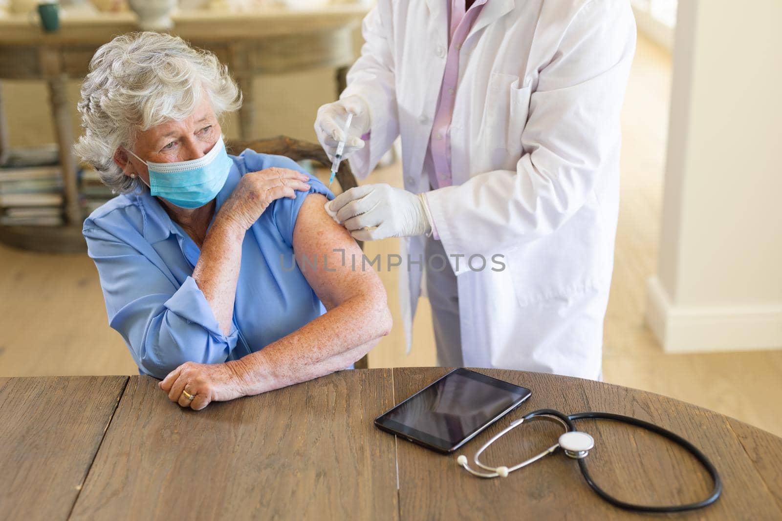 Senior caucasian male doctor vaccinating female patient wearing face mask by Wavebreakmedia