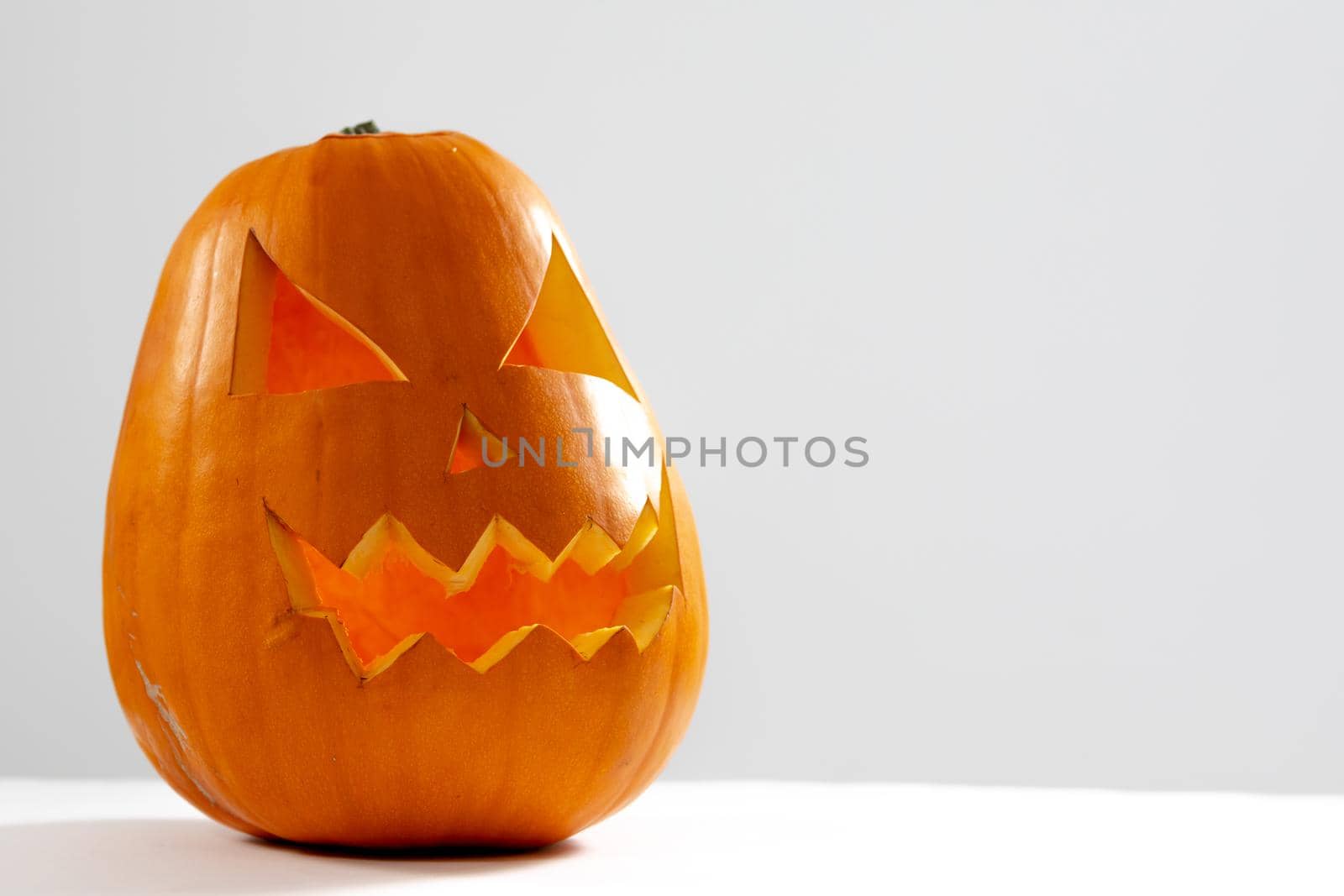 Composition of scary halloween carved orange pumpkin on white background. halloween tradition and celebration concept.