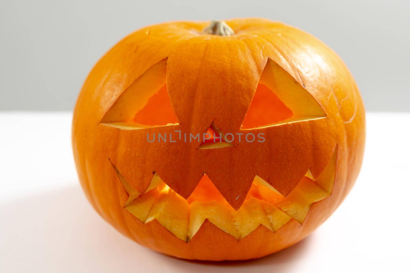 Composition of scary halloween carved orange pumpkin on white background. halloween tradition and celebration concept.