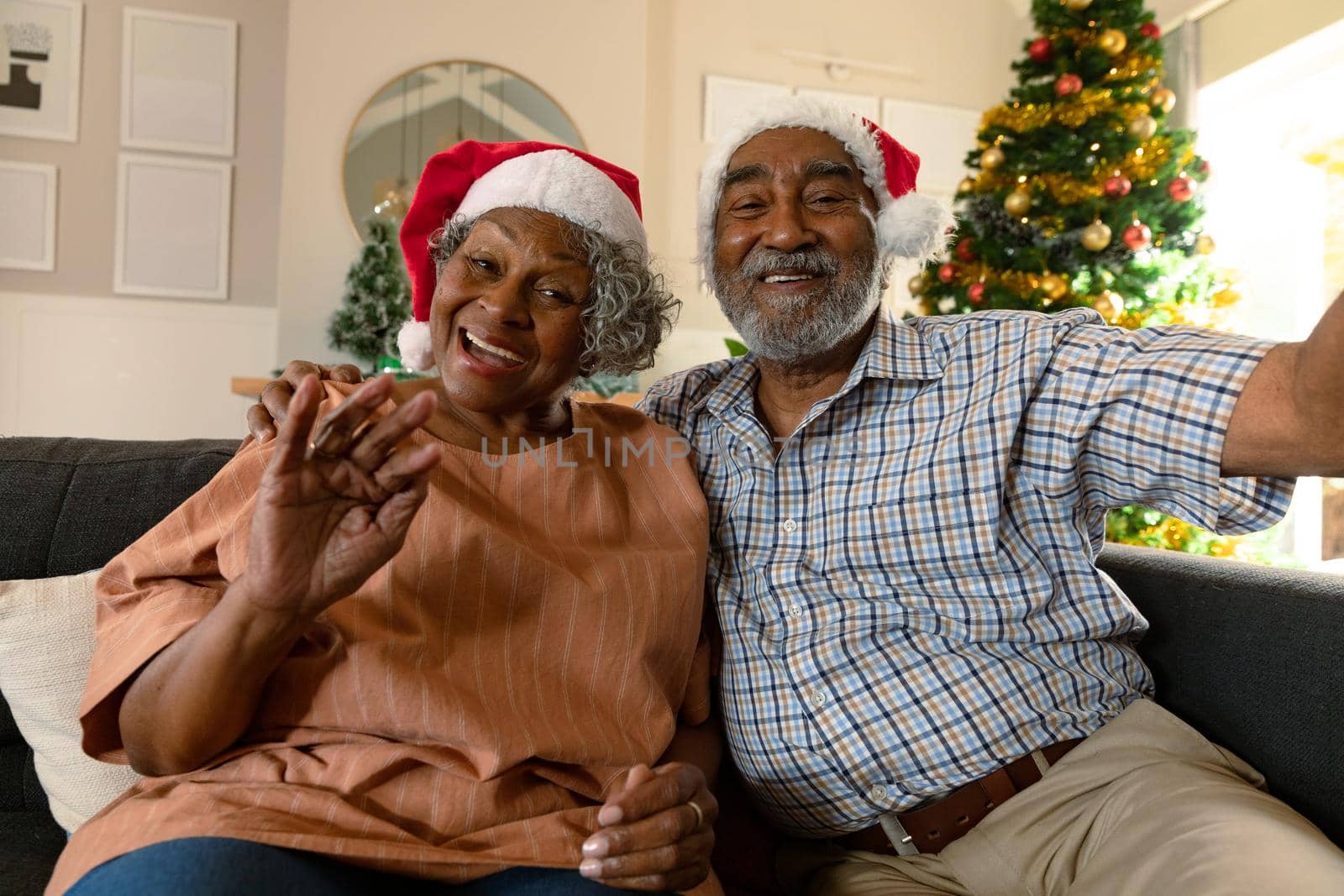 Happy african american couple wearing santa hats having video call at christmas time by Wavebreakmedia