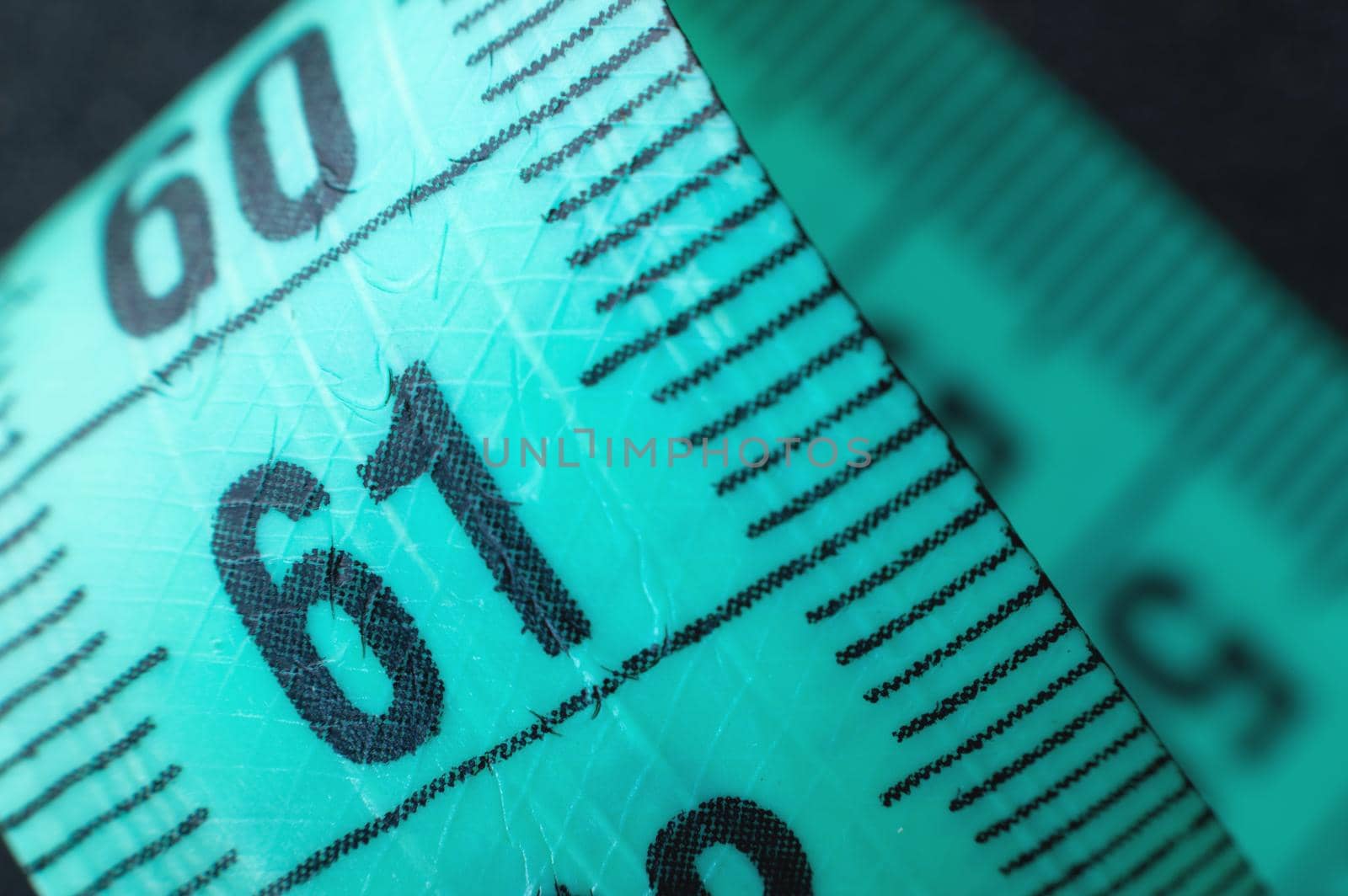 Close-up of rolled up tape measure on number 61. Slim waist and healthy weight concept.