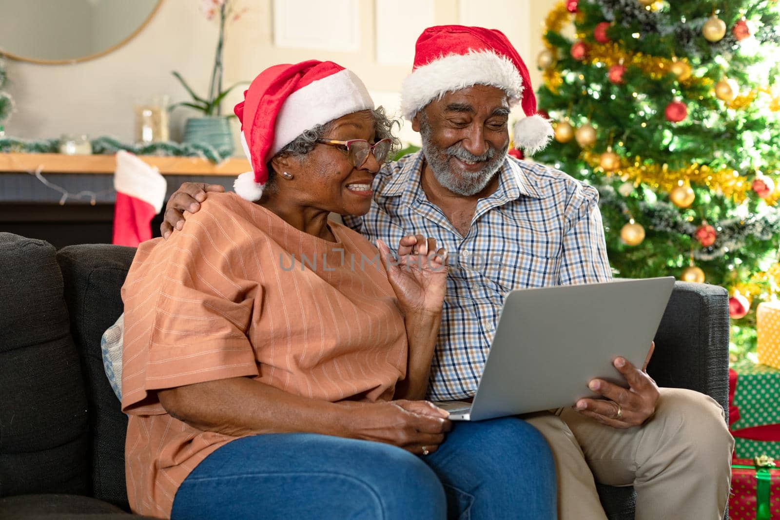 Happy african american couple wearing santa hats using laptop, having video call at christmas time by Wavebreakmedia