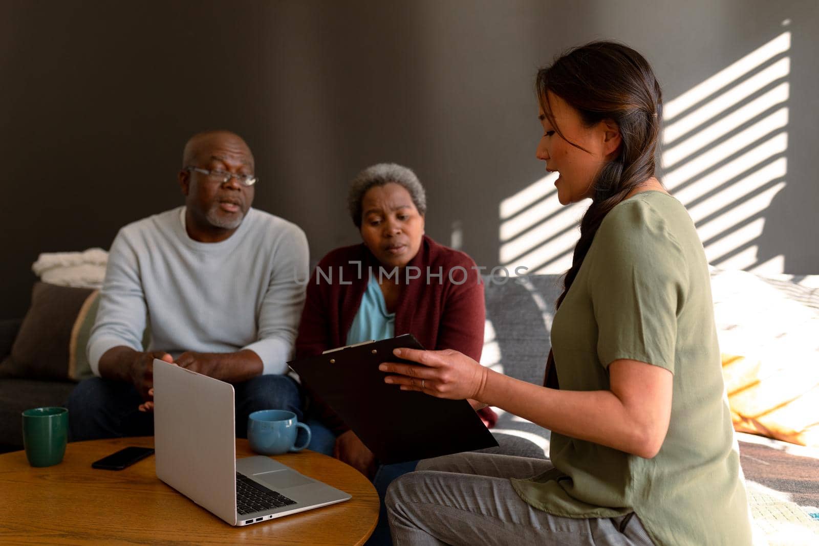 African american senior couple having meeting with asian female financial advisor at home. retirement lifestyle, elderly support and spending time at home.