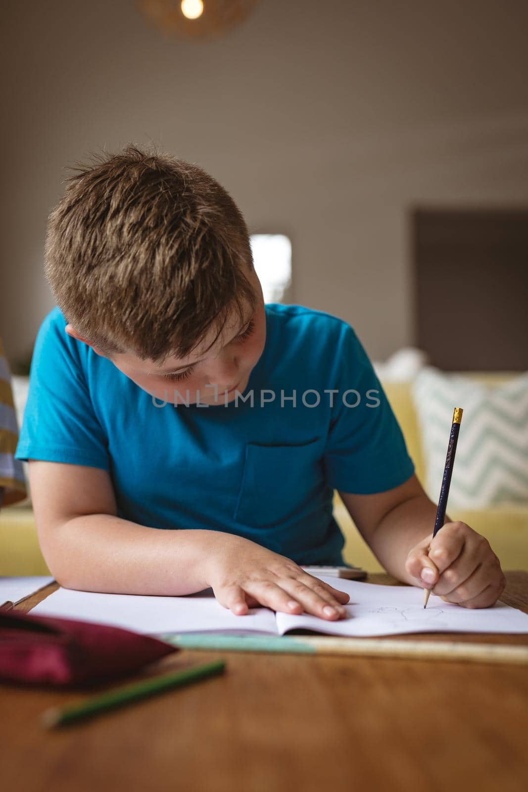 Caucasian boy drawing in his book sitting in the living room at home by Wavebreakmedia