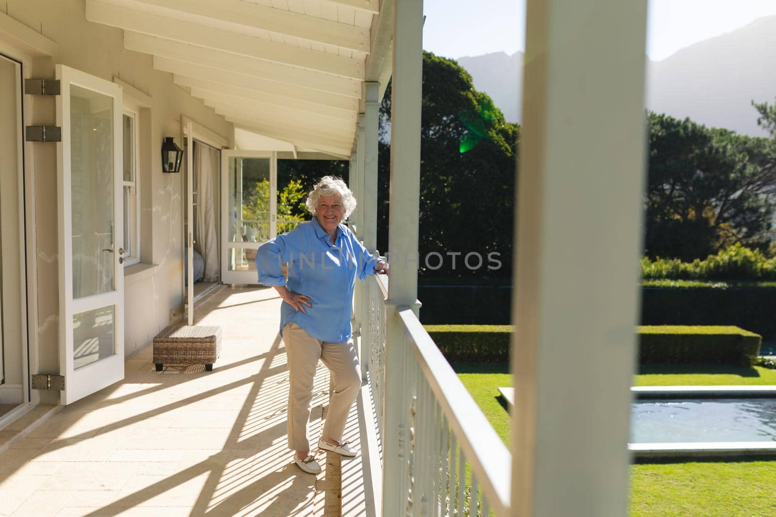 Portrait of senior caucasian woman standing on balcony and smiling. retreat, retirement and happy senior lifestyle concept.