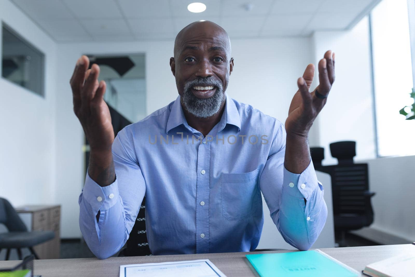 Portrait of african american businessman sitting at desk and having video call. online meeting, working in isolation during quarantine lockdown.