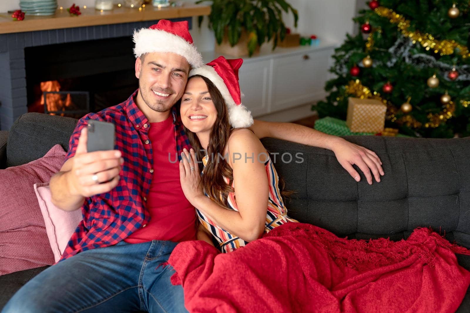 Happy caucasian couple wearing santa hats and having video call on smartphone at christmas time by Wavebreakmedia