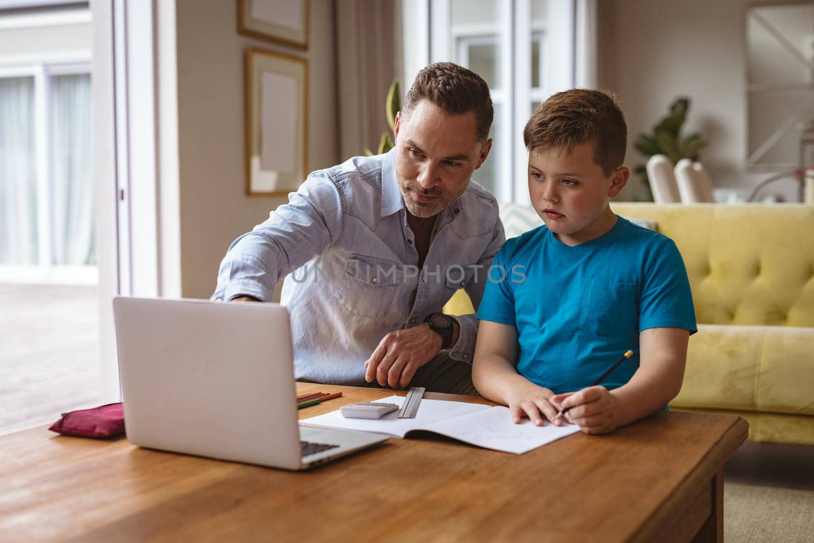 Caucasian father using laptop to help his son with homework at home by Wavebreakmedia