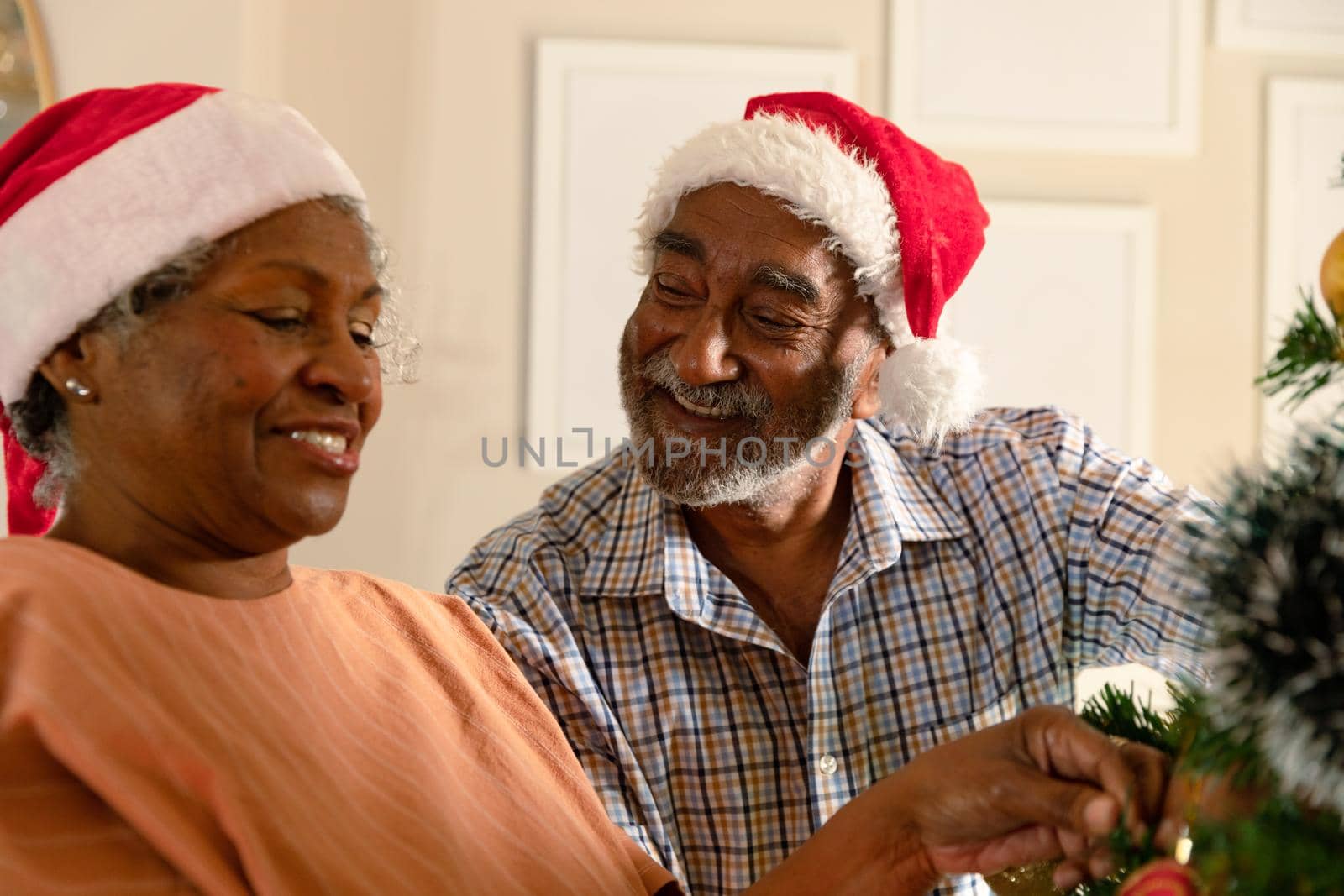 Happy african american senior couple decorating christmas tree. family christmas time and festivity together at home.