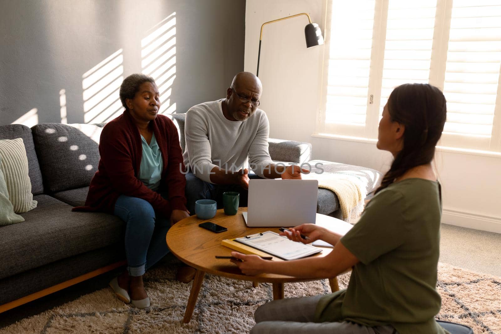 African american senior couple having meeting with asian female financial advisor at home. retirement lifestyle, elderly support and spending time at home.