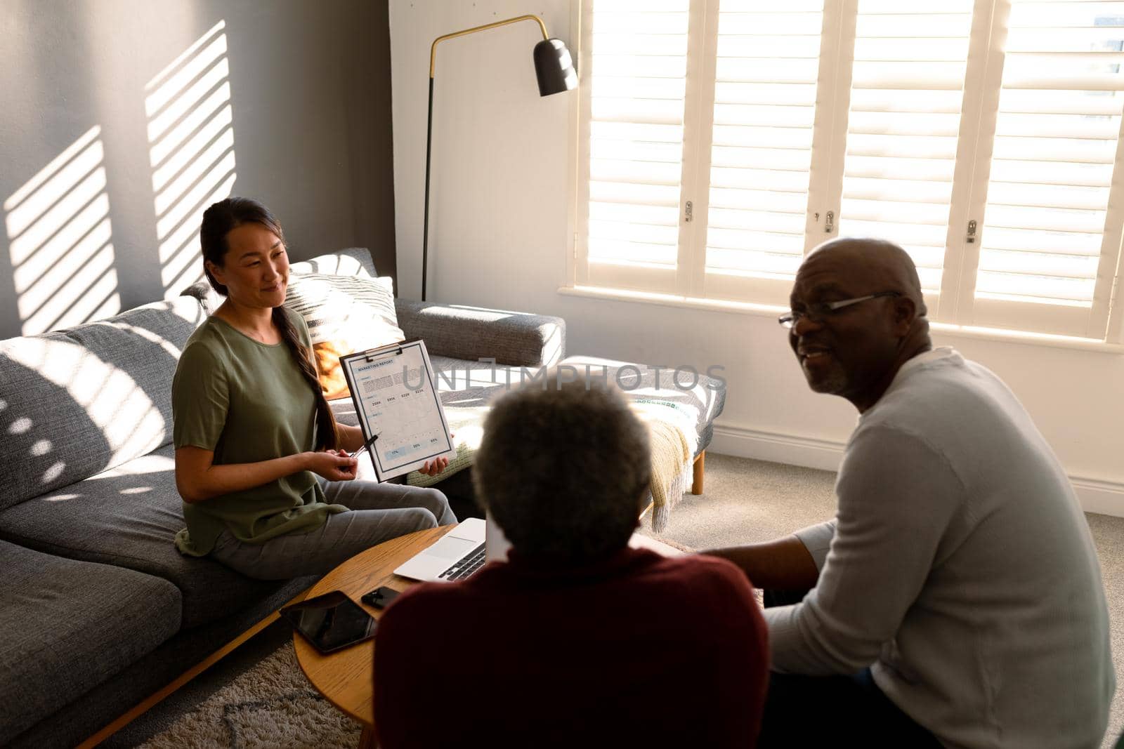 African american senior couple having meeting with asian female financial advisor at home. retirement lifestyle, elderly support and spending time at home.