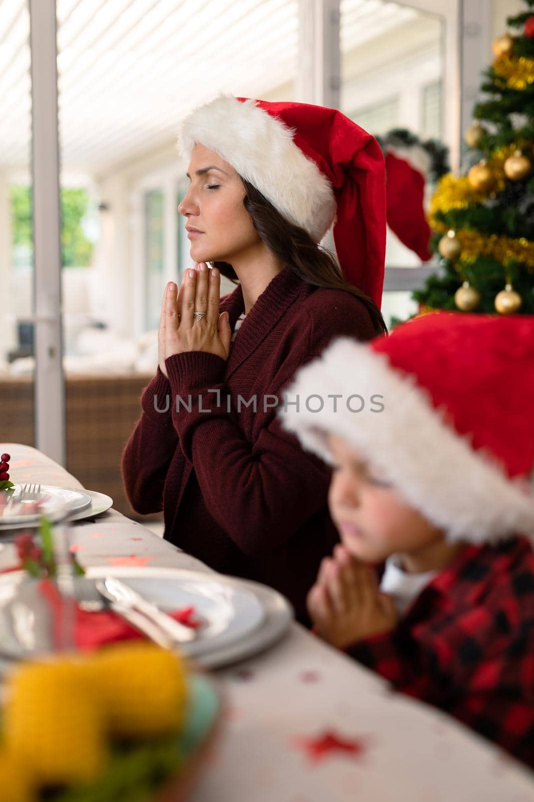 Caucasian boy and his mother praying together at christmas table by Wavebreakmedia