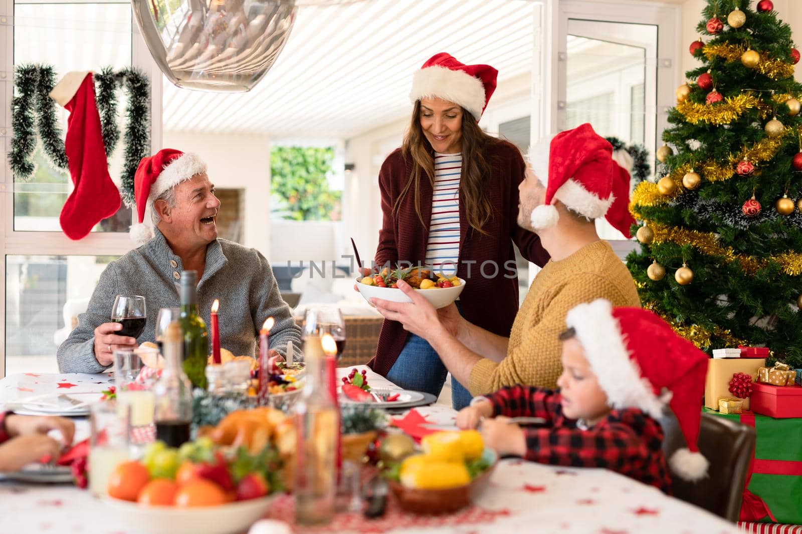 Caucasian multi generation family wearing santa hats having christmas meal. family christmas time and festivity together at home.