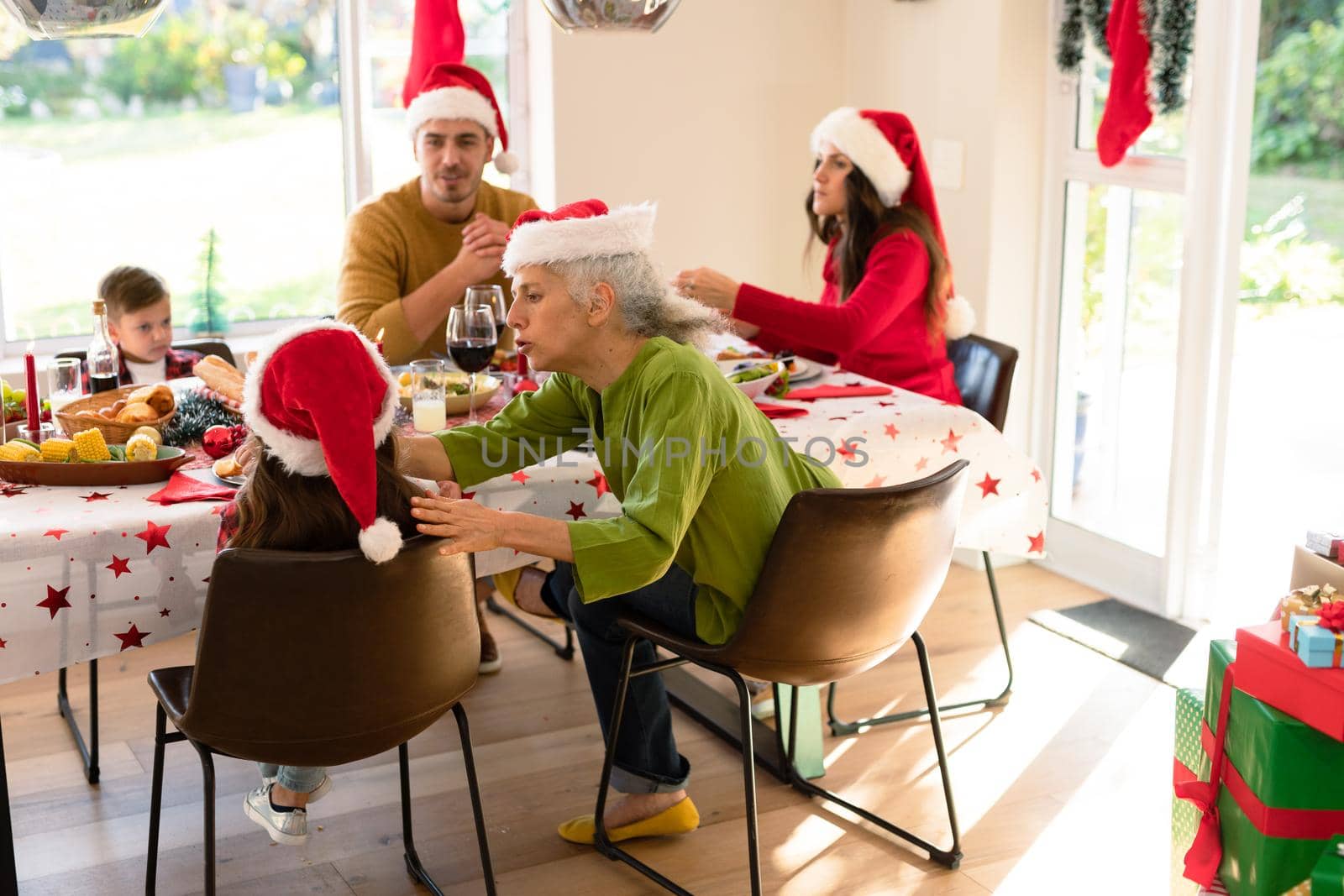 Caucasian multi generation family wearing santa hats having christmas meal. family christmas time and festivity together at home.