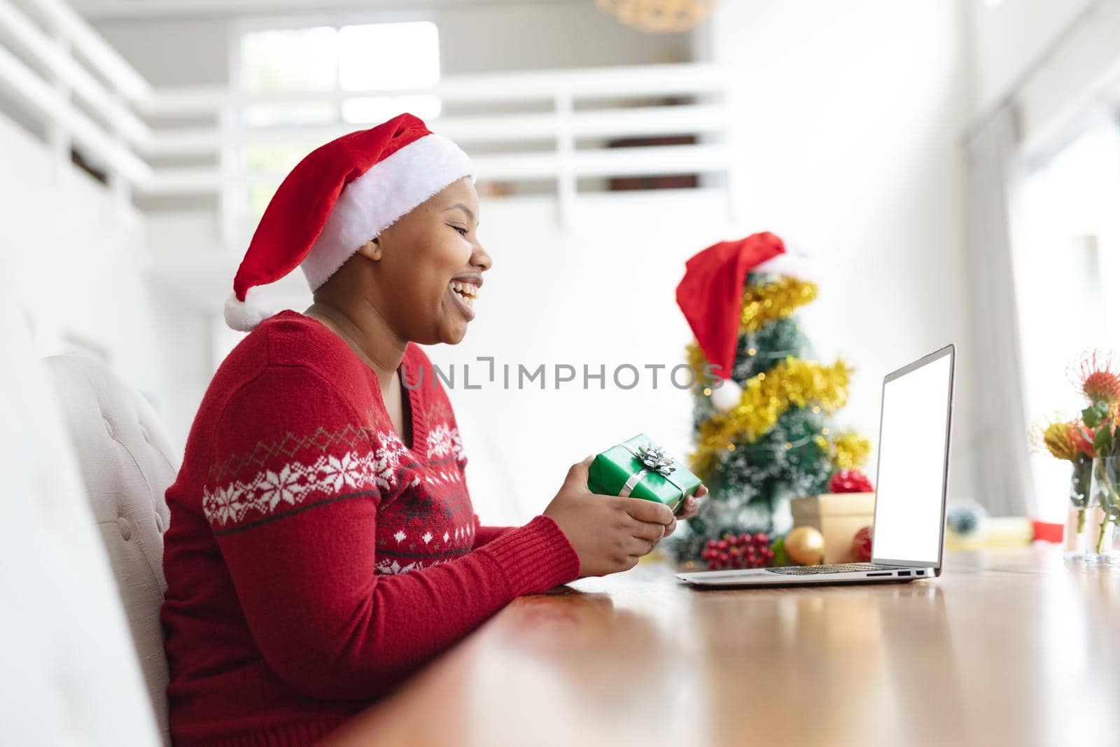 Happy african american plus size woman in santa hat making christmas video call on laptop by Wavebreakmedia
