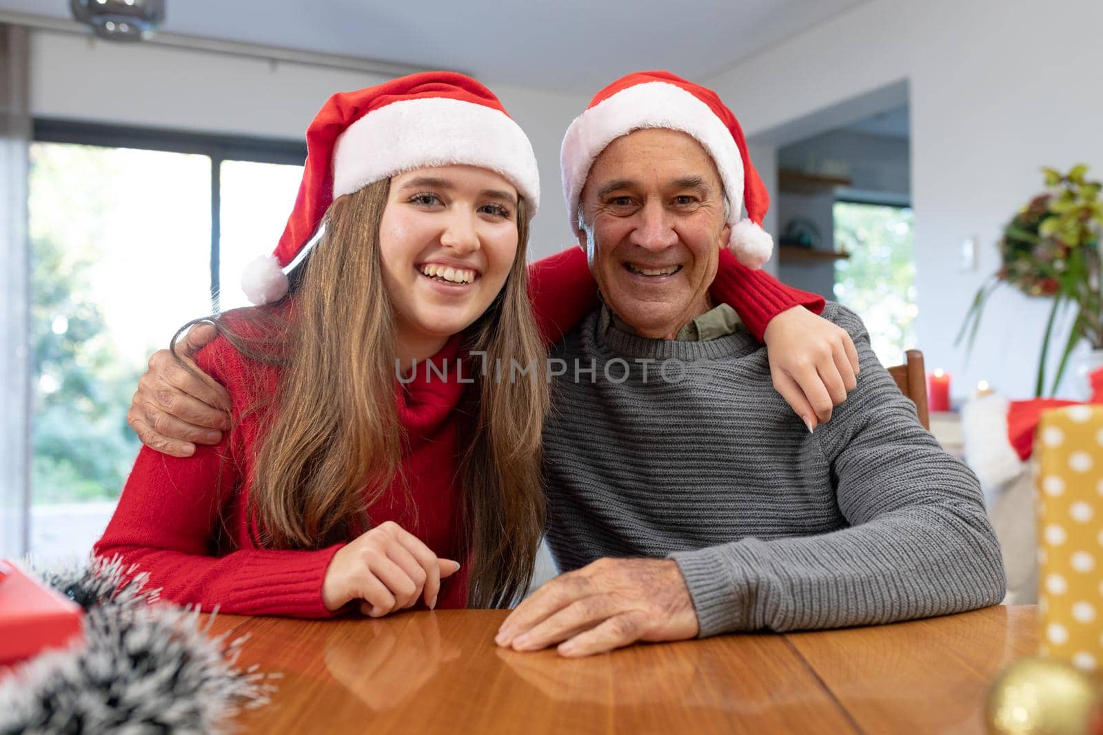 Caucasian woman and senior man wearing santa hats having video call at christmas time by Wavebreakmedia